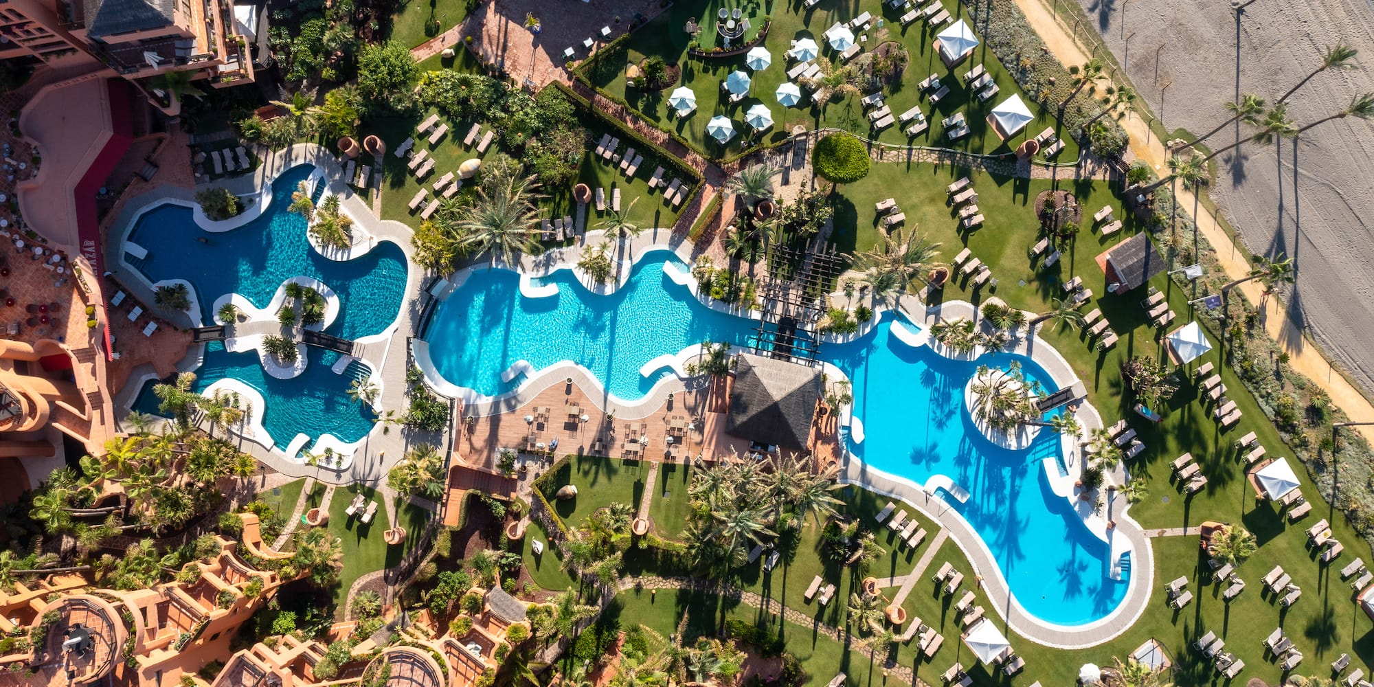 an aerial view of a resort with swimming pools and lawns