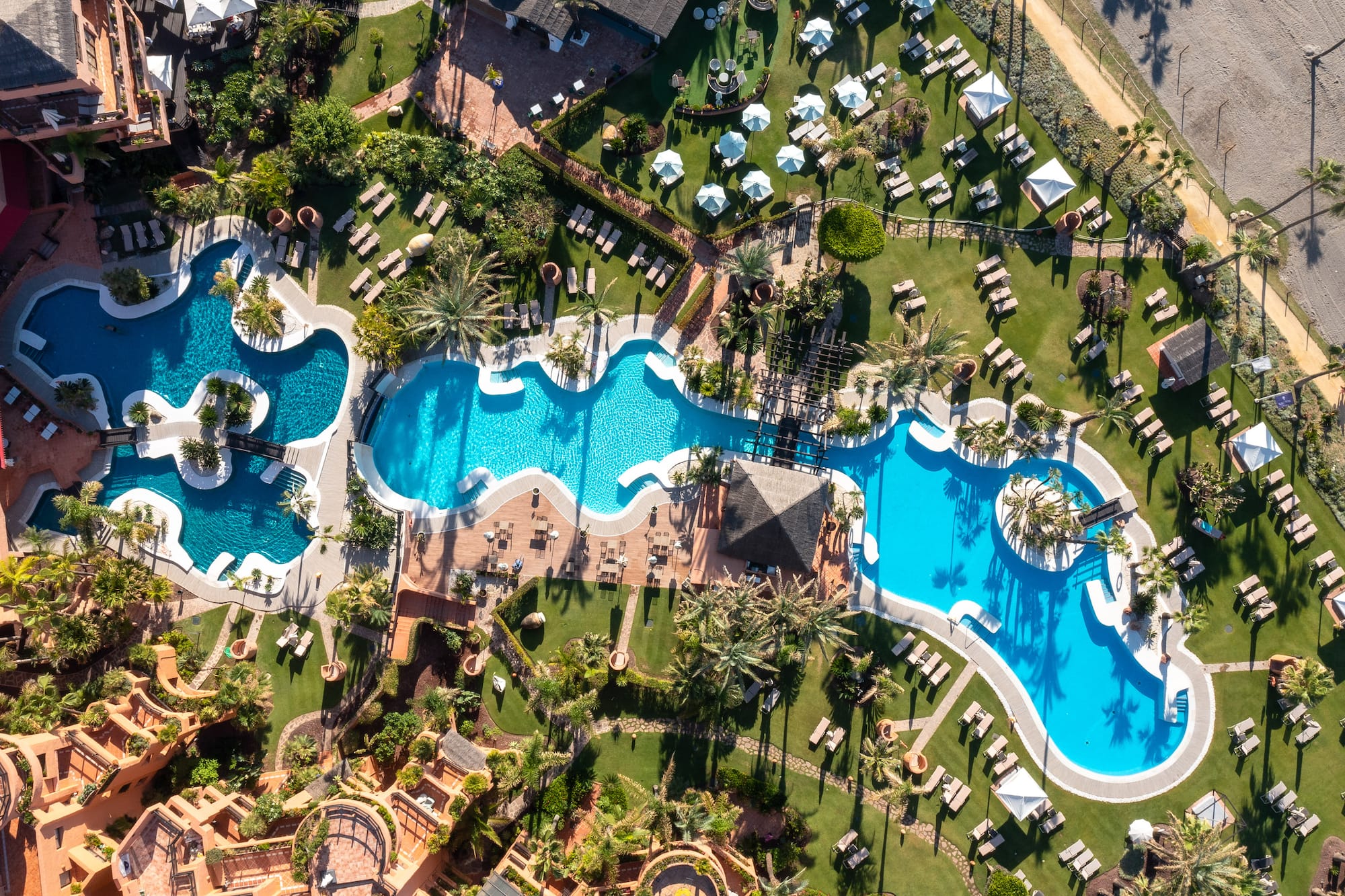 an aerial view of a resort with swimming pools and lawns