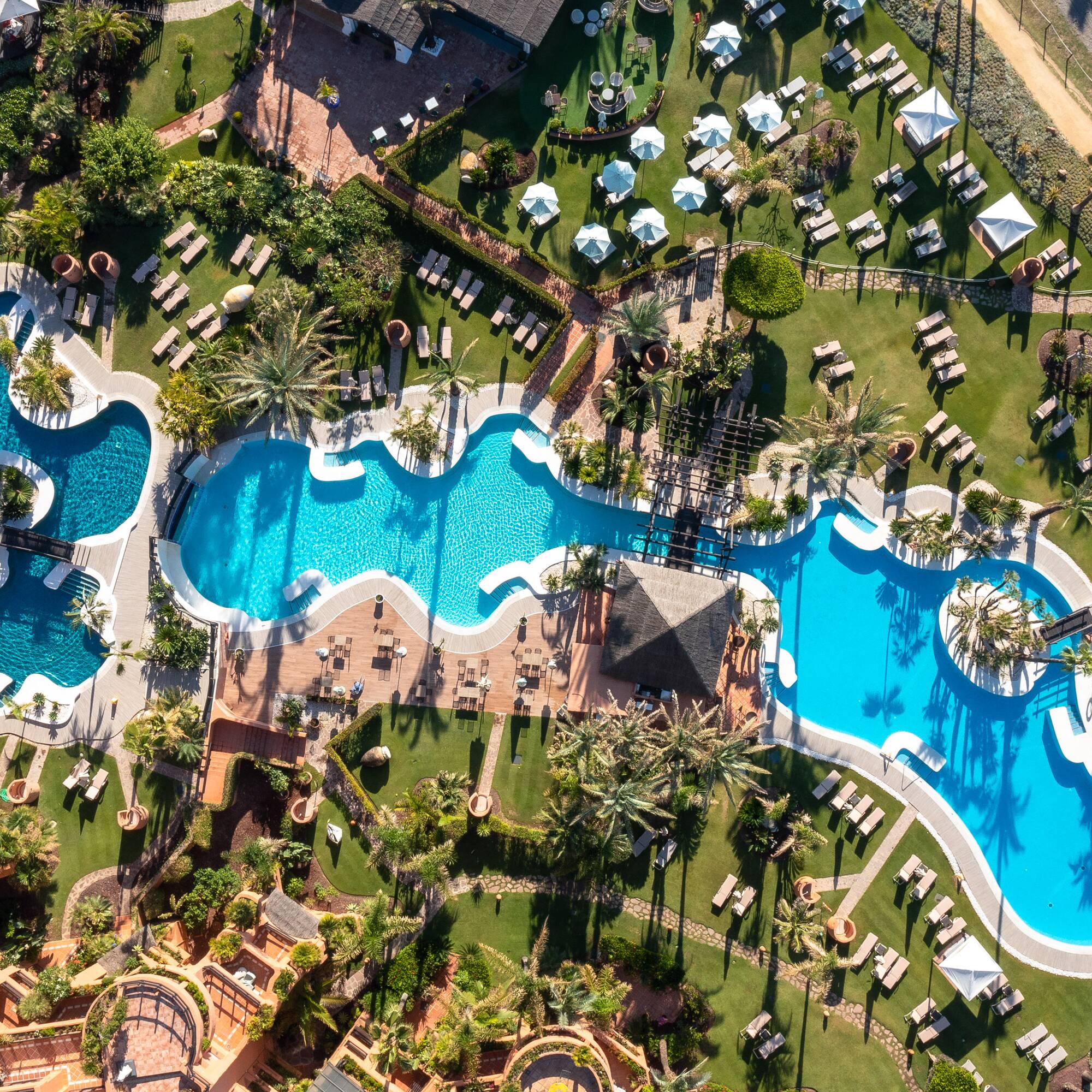 an aerial view of a resort with swimming pools and lawns