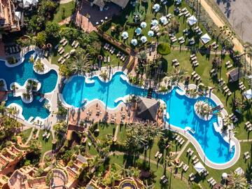 an aerial view of a resort with swimming pools and lawns