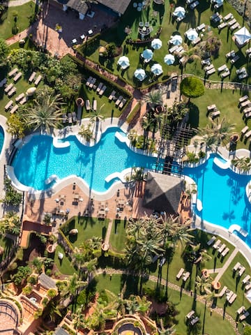 an aerial view of a resort with swimming pools and lawns