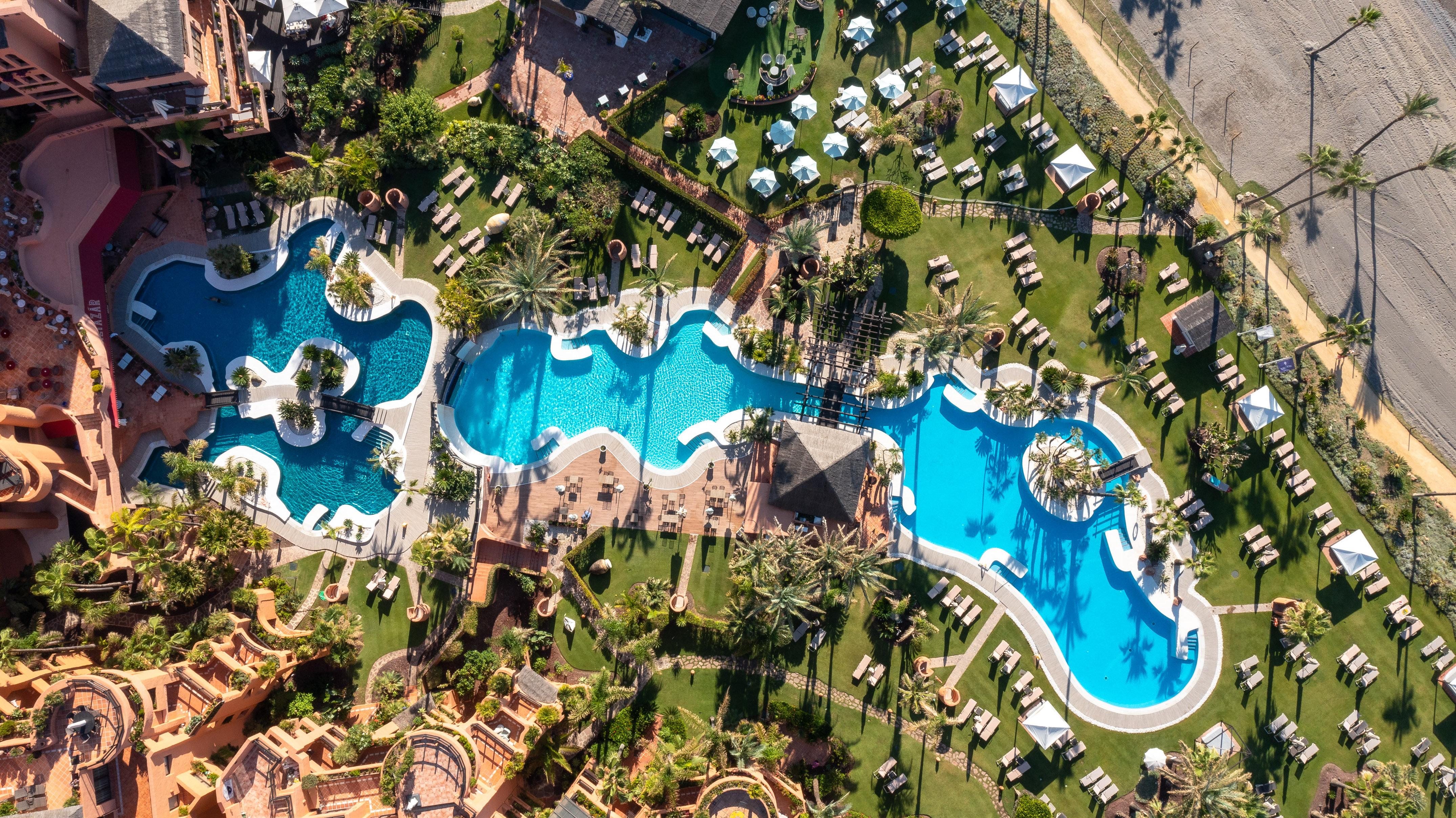 an aerial view of a resort with swimming pools and lawns