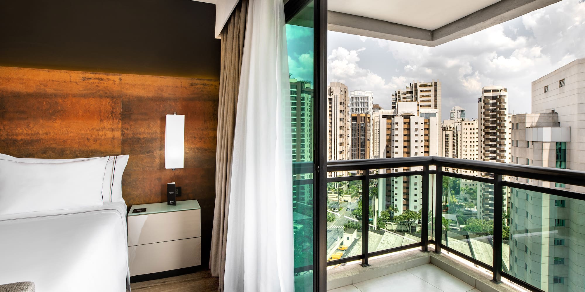 a room with a balcony and a bed and a view of a city