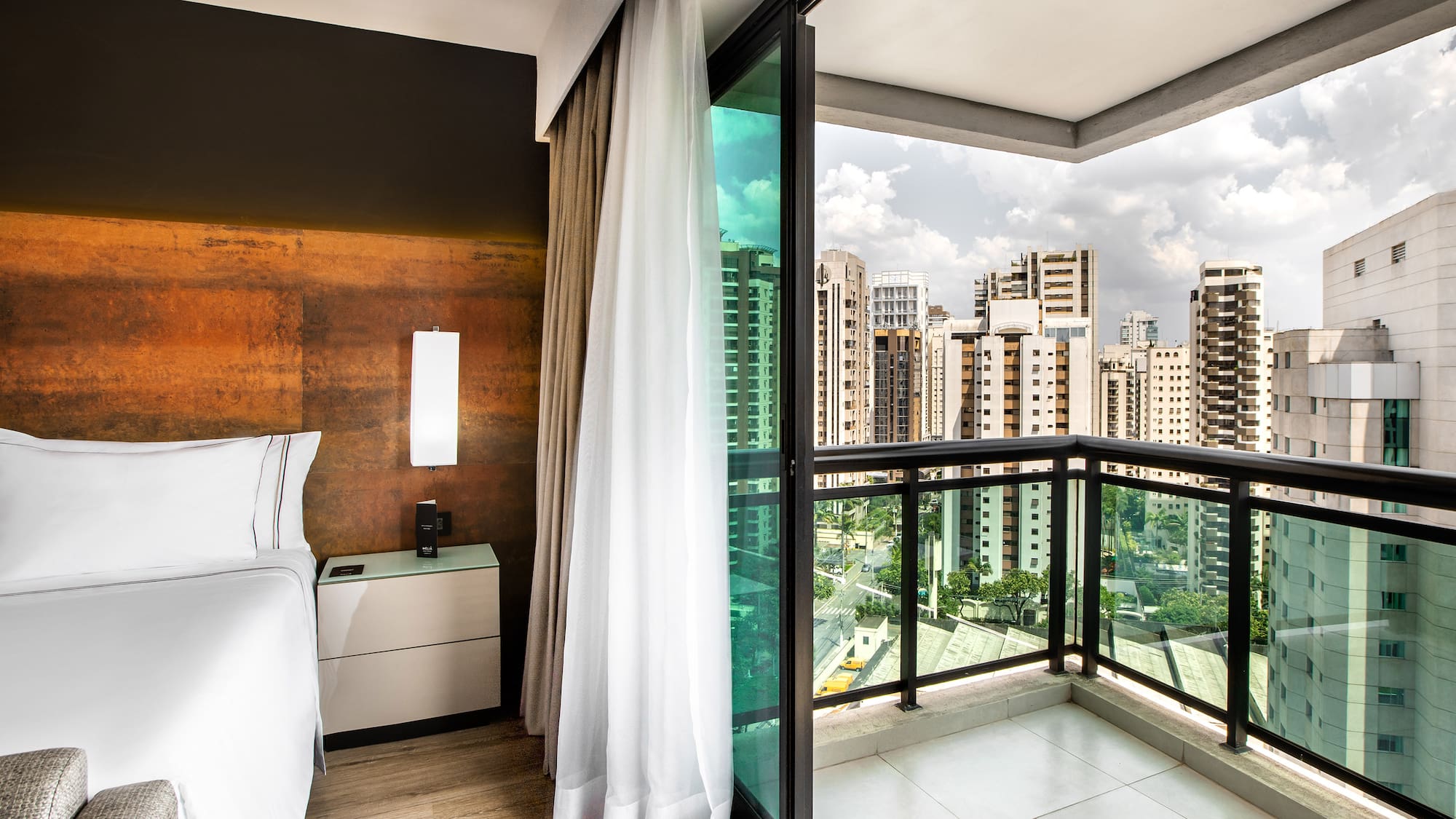 a room with a balcony and a bed and a view of a city