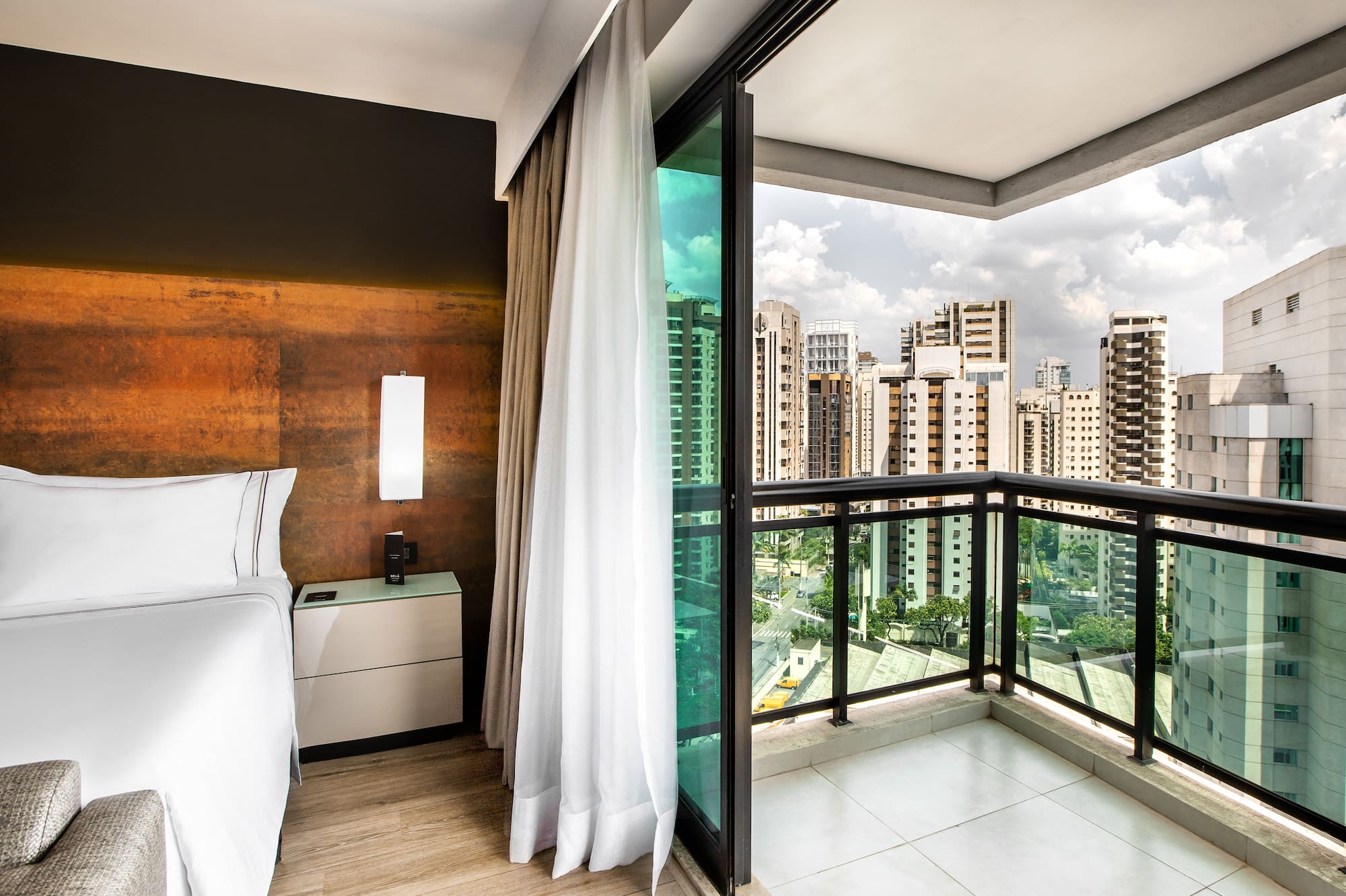 a room with a balcony and a bed and a view of a city