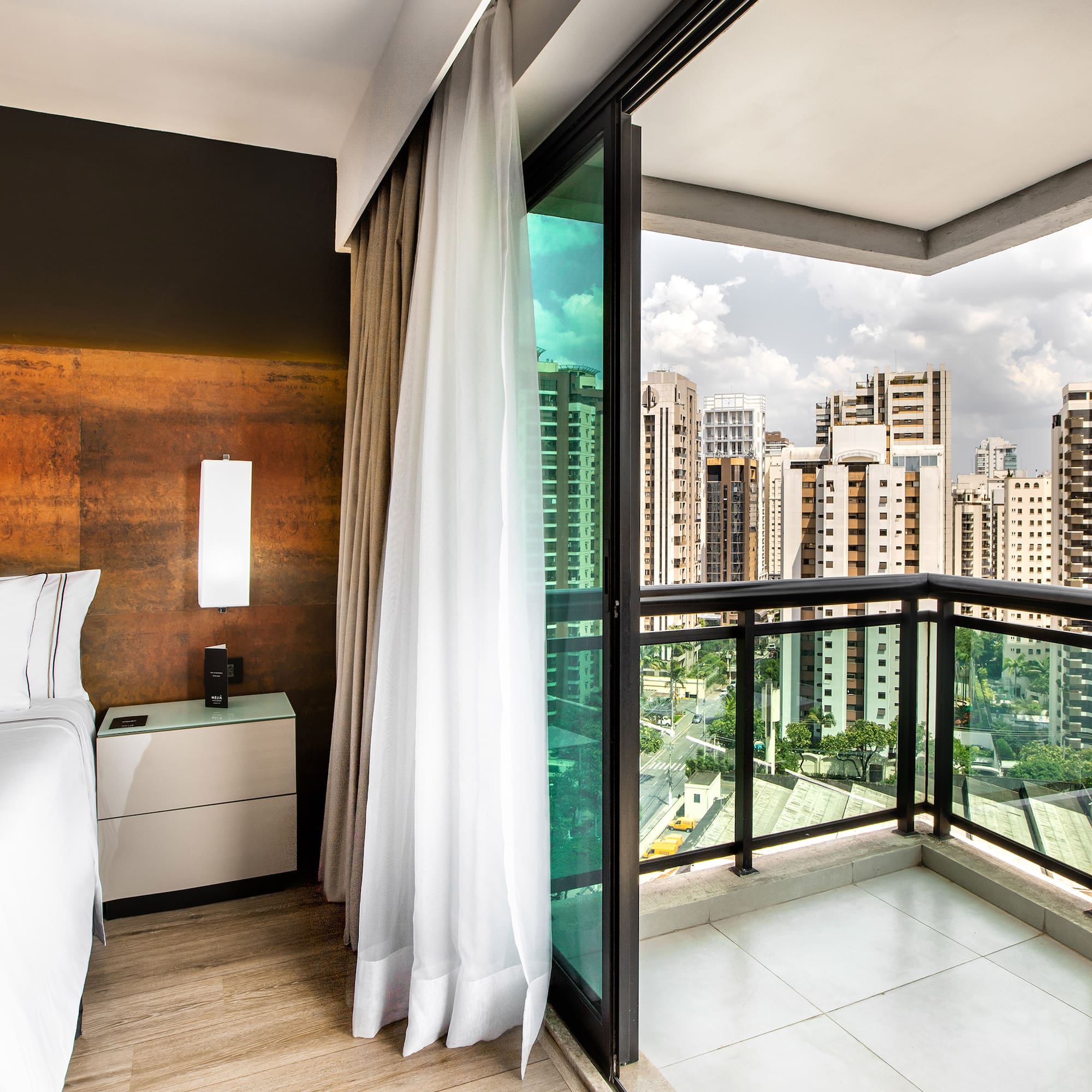 a room with a balcony and a bed and a view of a city