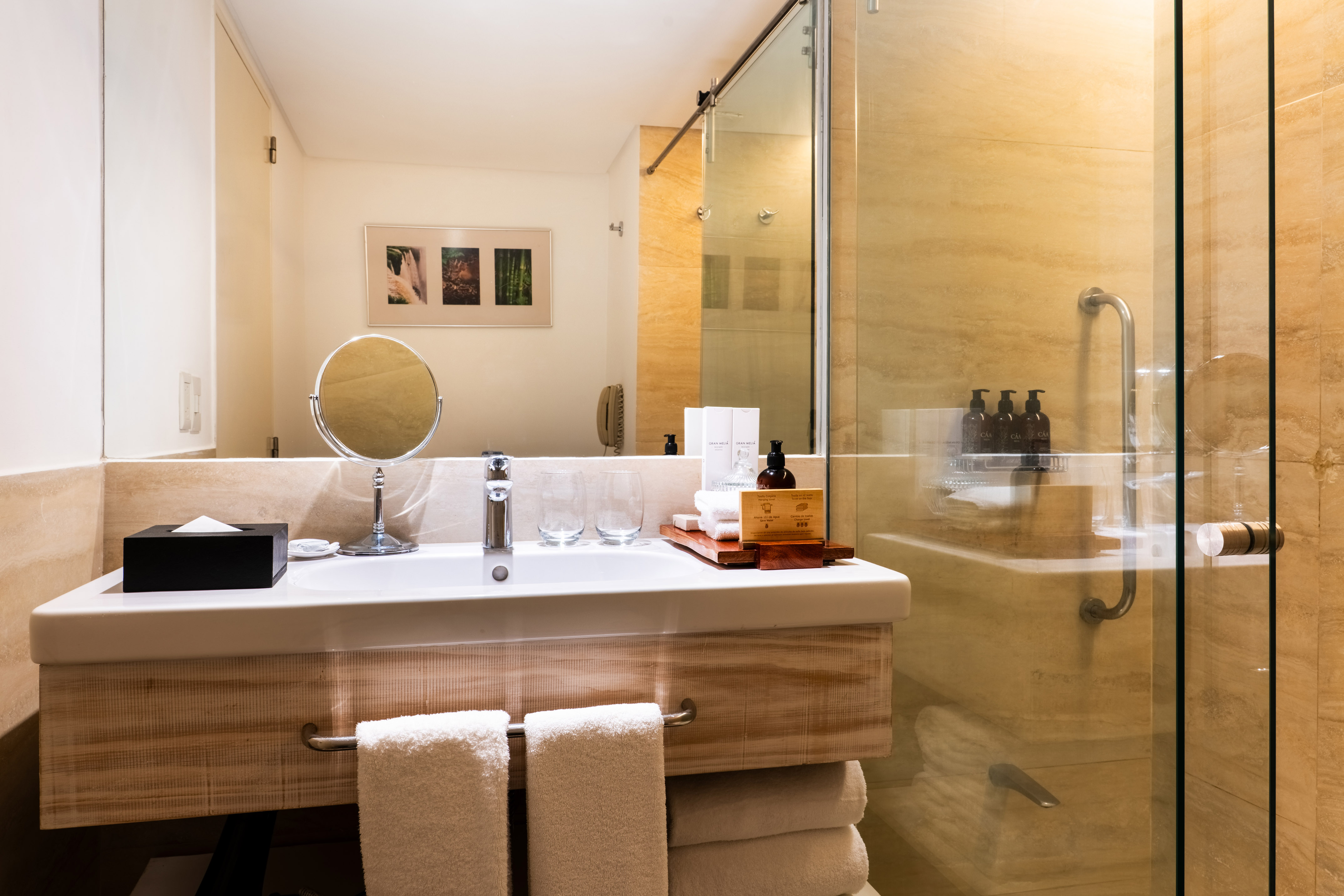 Modern hotel bathroom with sink, wooden vanity, large mirror, and glass shower. - Family Room – Jungle View - Gran Meliá Iguazú, Εθνικό Πάρκο Iguazú