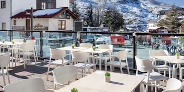 a table and chairs outside with a snowy mountain in the background