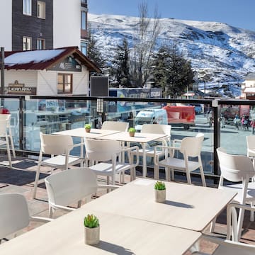 a table and chairs outside with a snowy mountain in the background