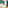 Hotel room with white bed, teal walls, arched window, and wooden table.