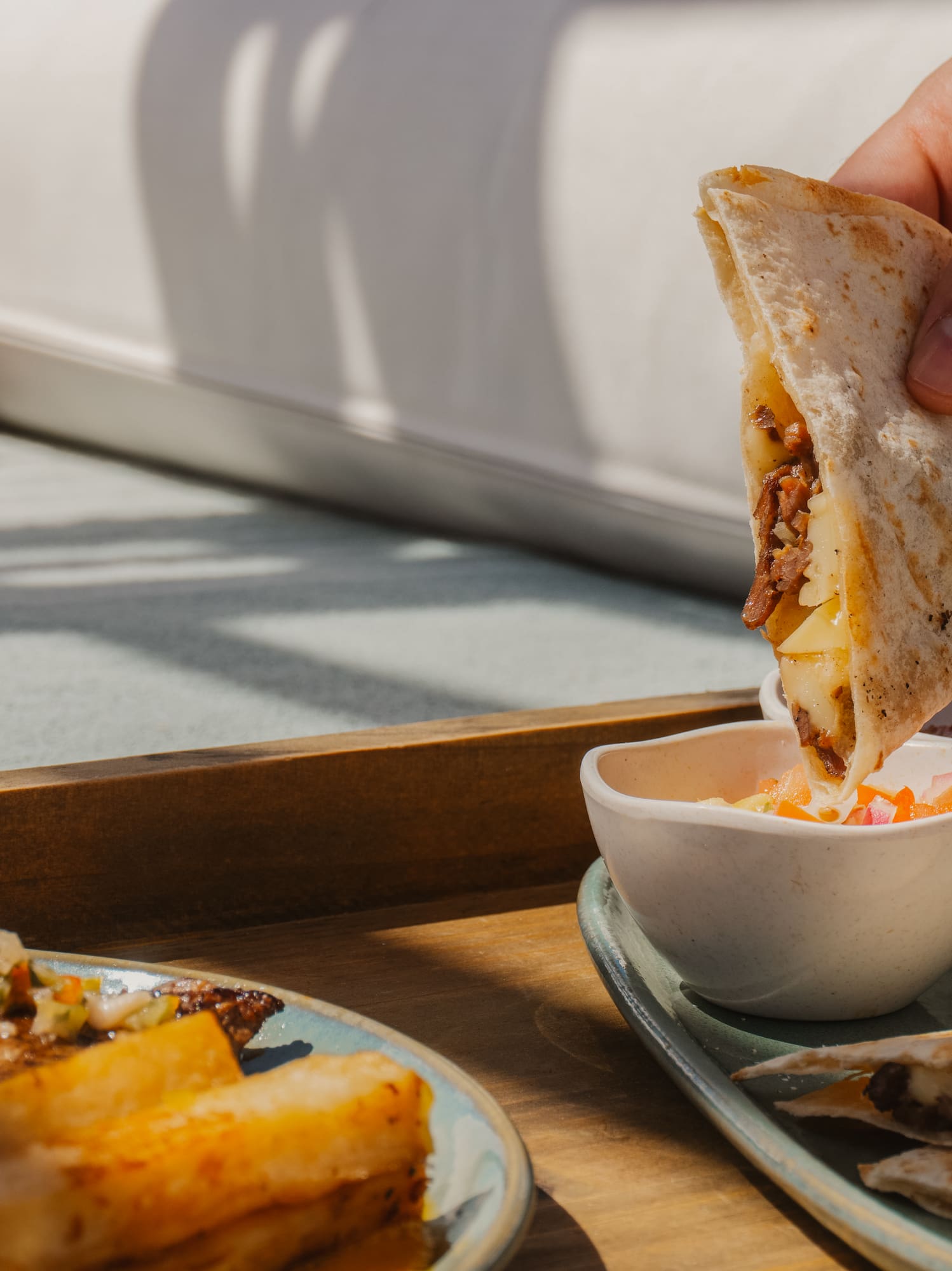 a person holding a quesadilla over a plate of food