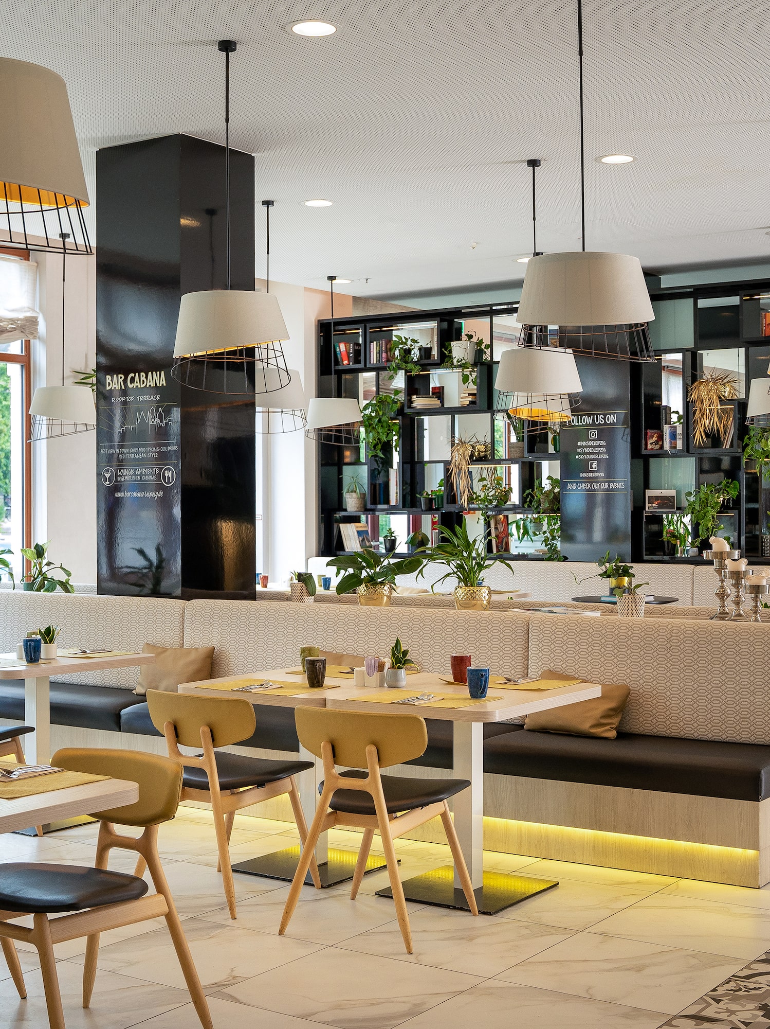 Modern Bar Cabana restaurant interior with plants, stylish lighting, and booths.