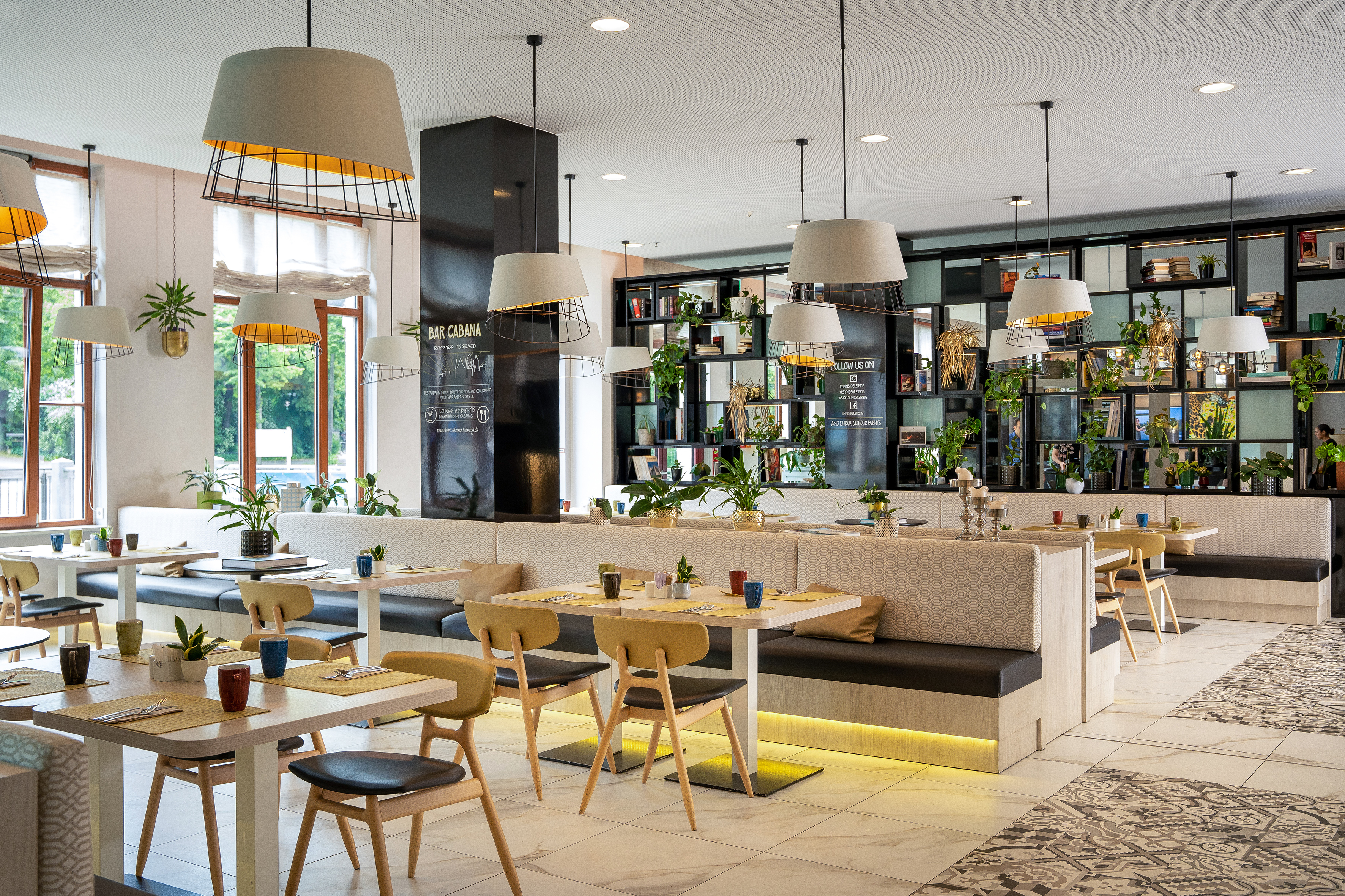 Modern Bar Cabana restaurant interior with plants, stylish lighting, and booths.