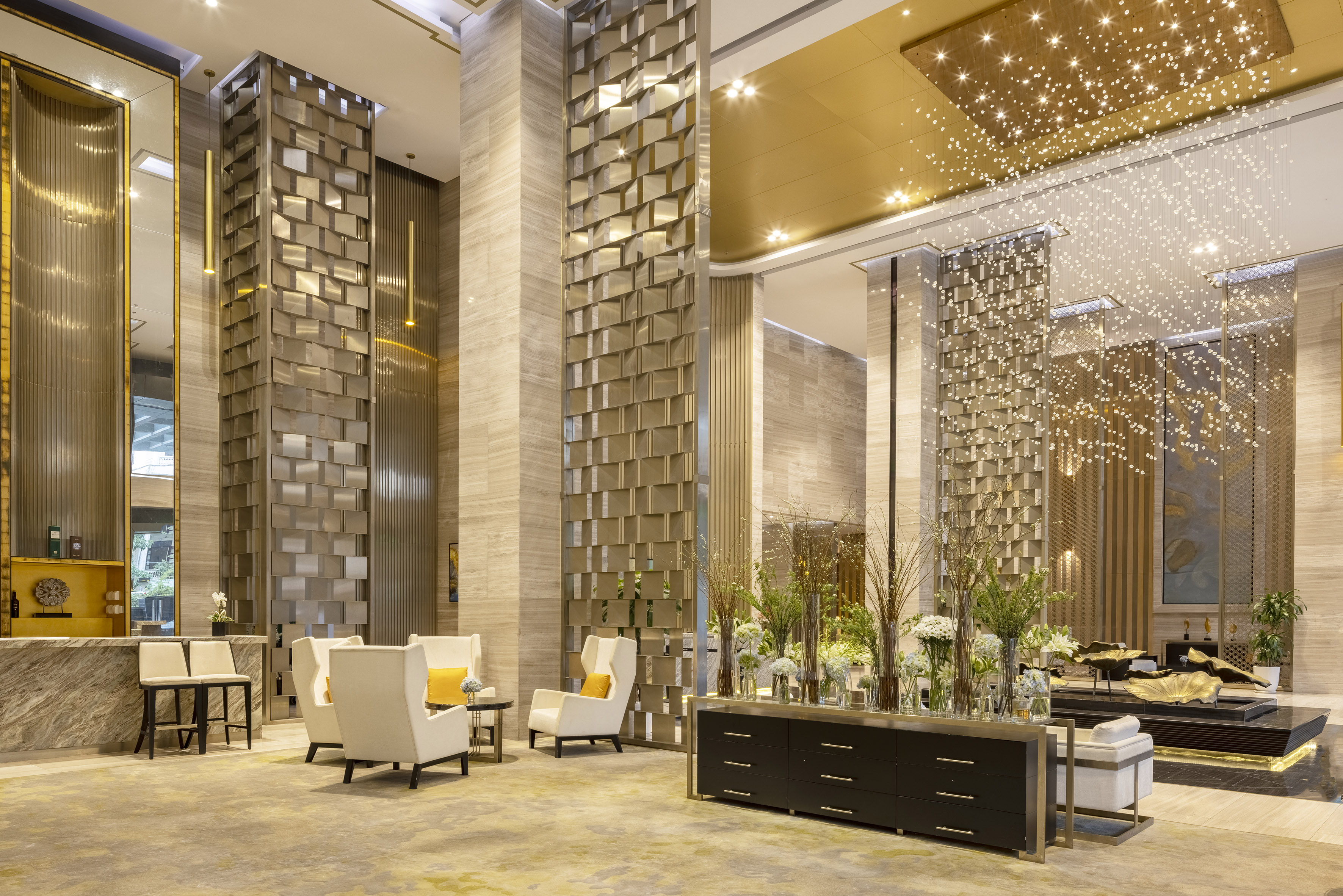 Modern luxury hotel lobby with gold ceiling, marble, and star-effect chandelier.