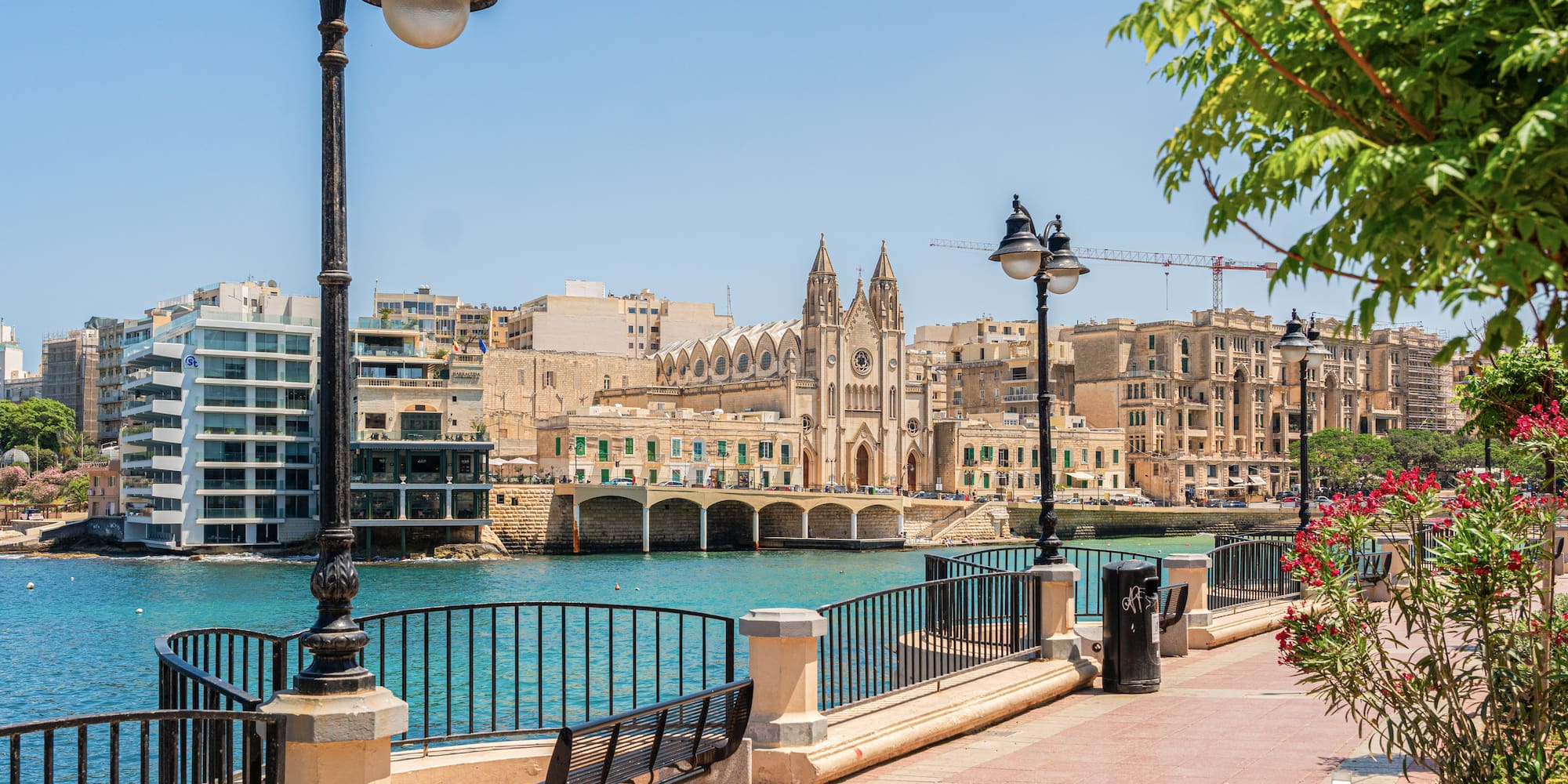 a walkway with a bridge and buildings by the water