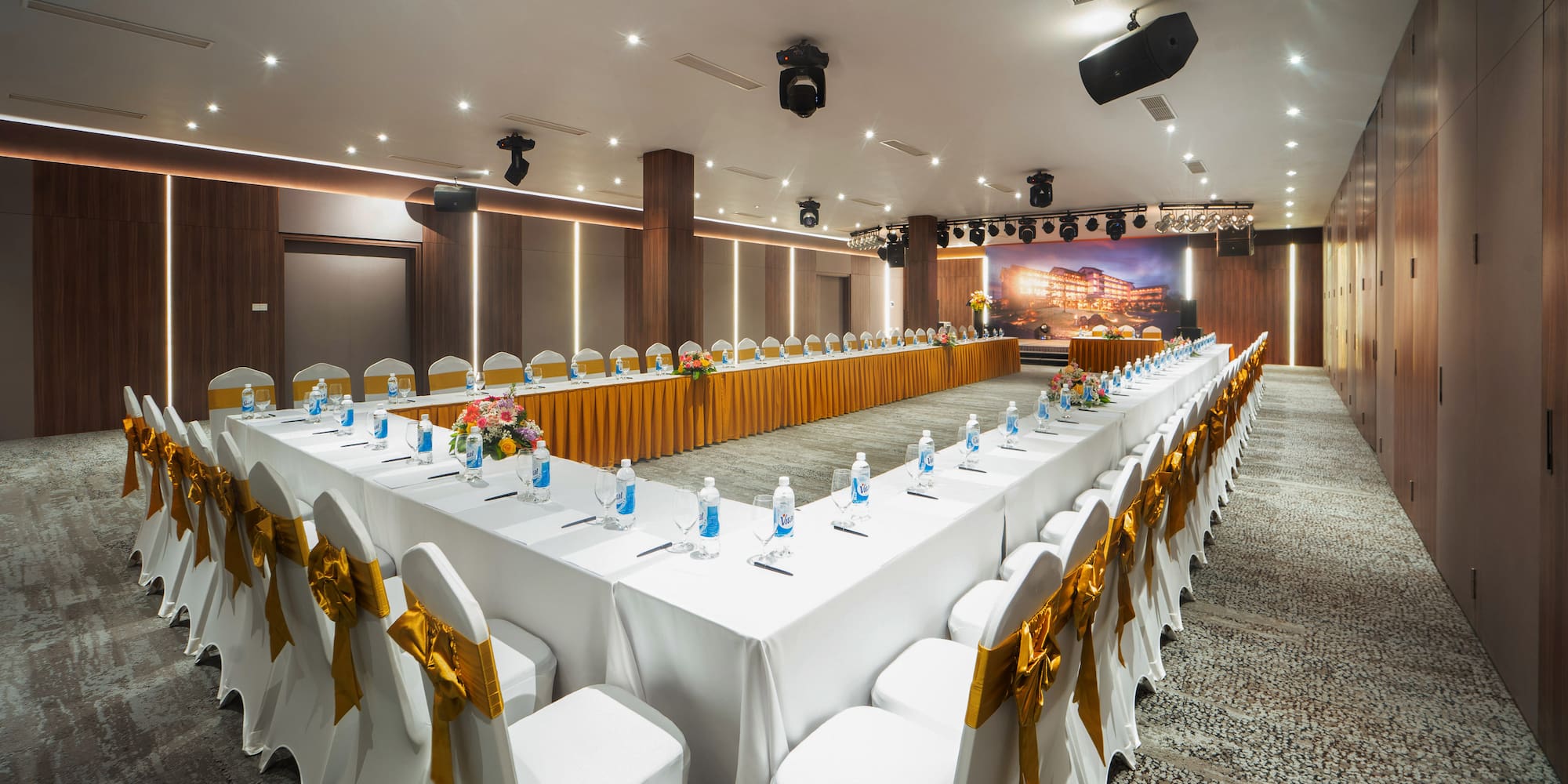 a long white table with white chairs and yellow bows