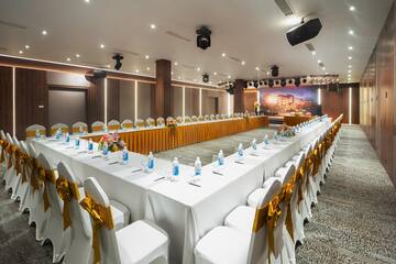 a long white table with white chairs and yellow bows