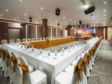 a long white table with white chairs and yellow bows