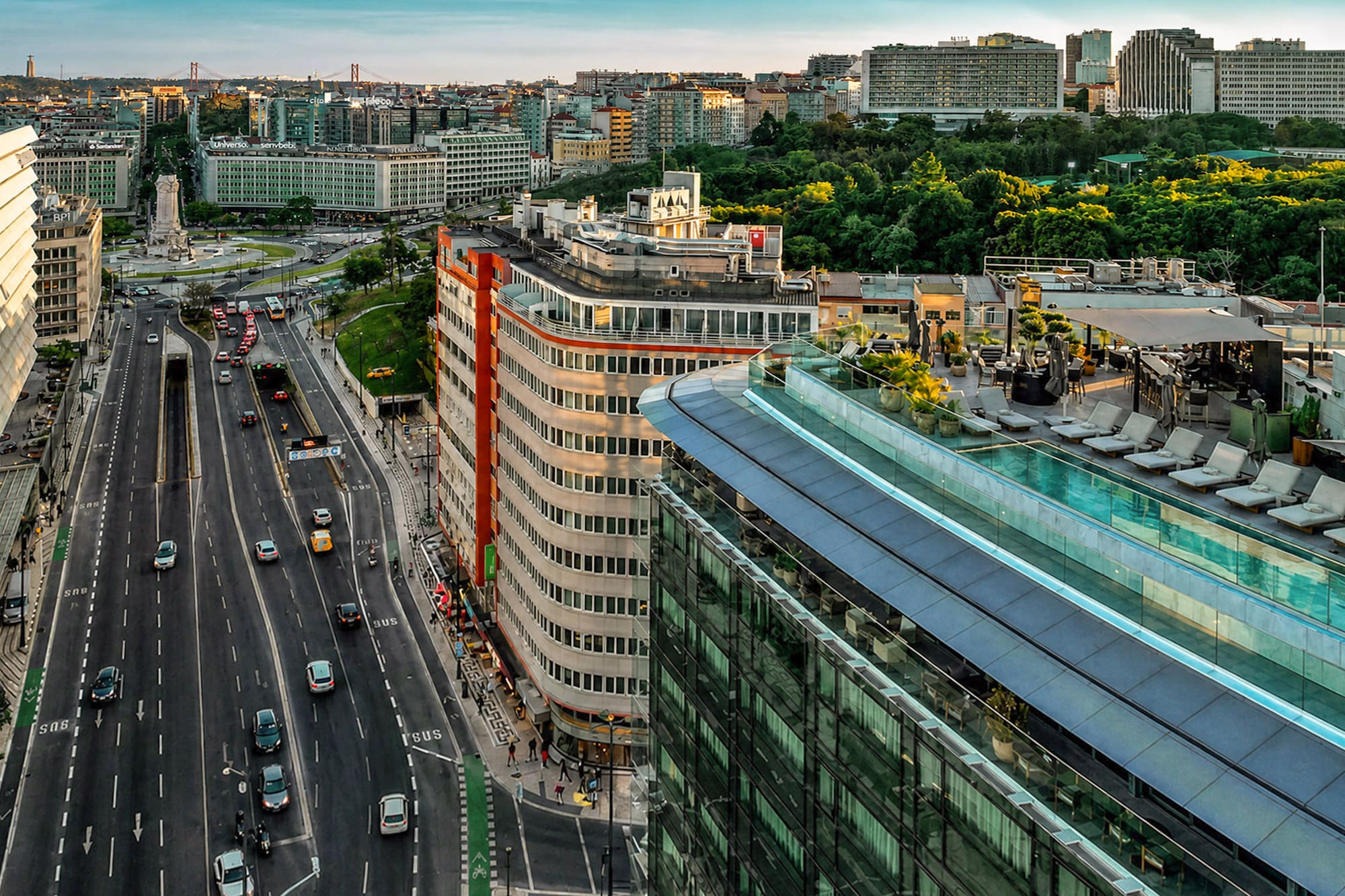 Aerial view of Lisbon city with busy highway, modern buildings, and rooftop pool.