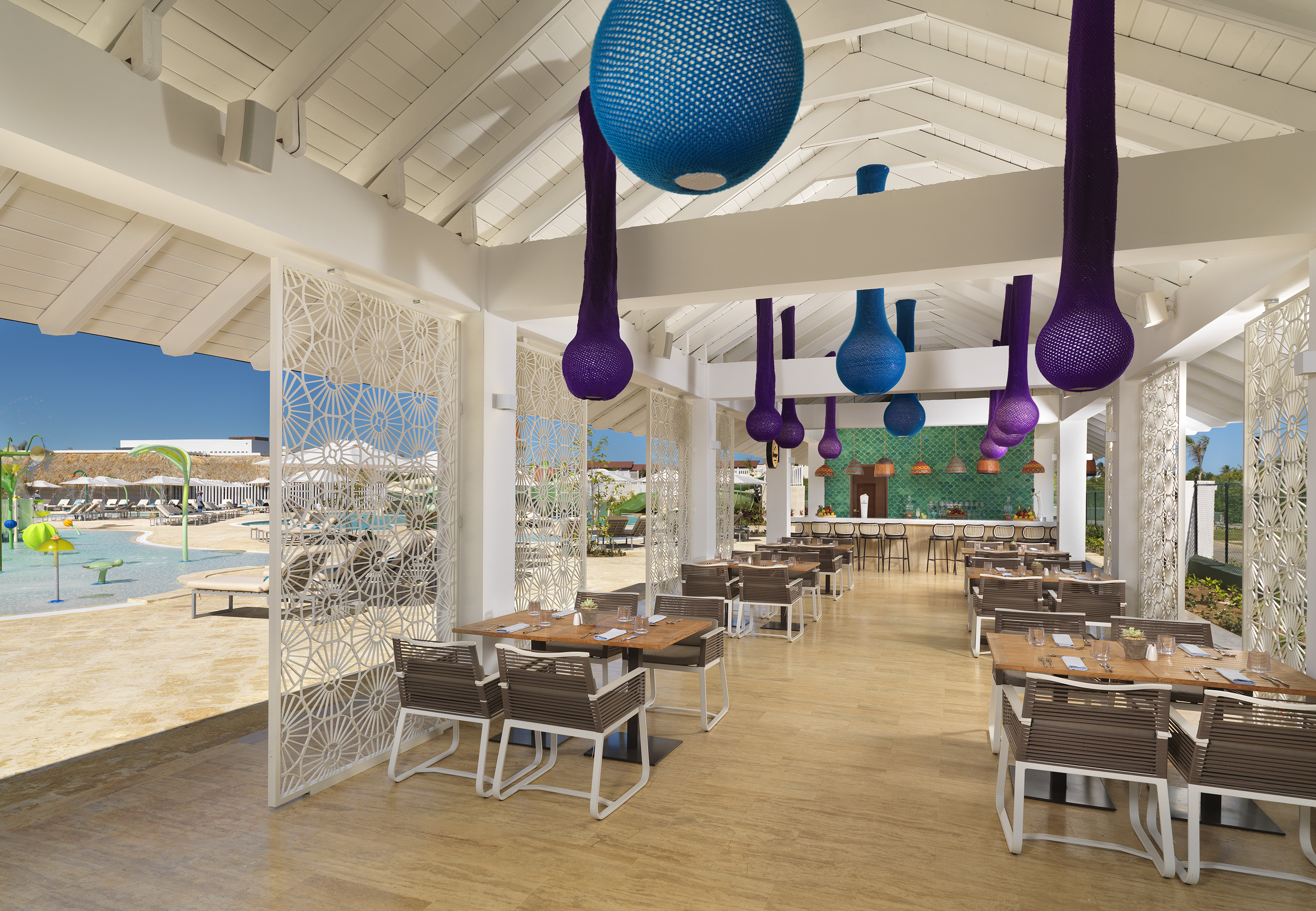 Modern resort restaurant with vibrant decor and poolside views.