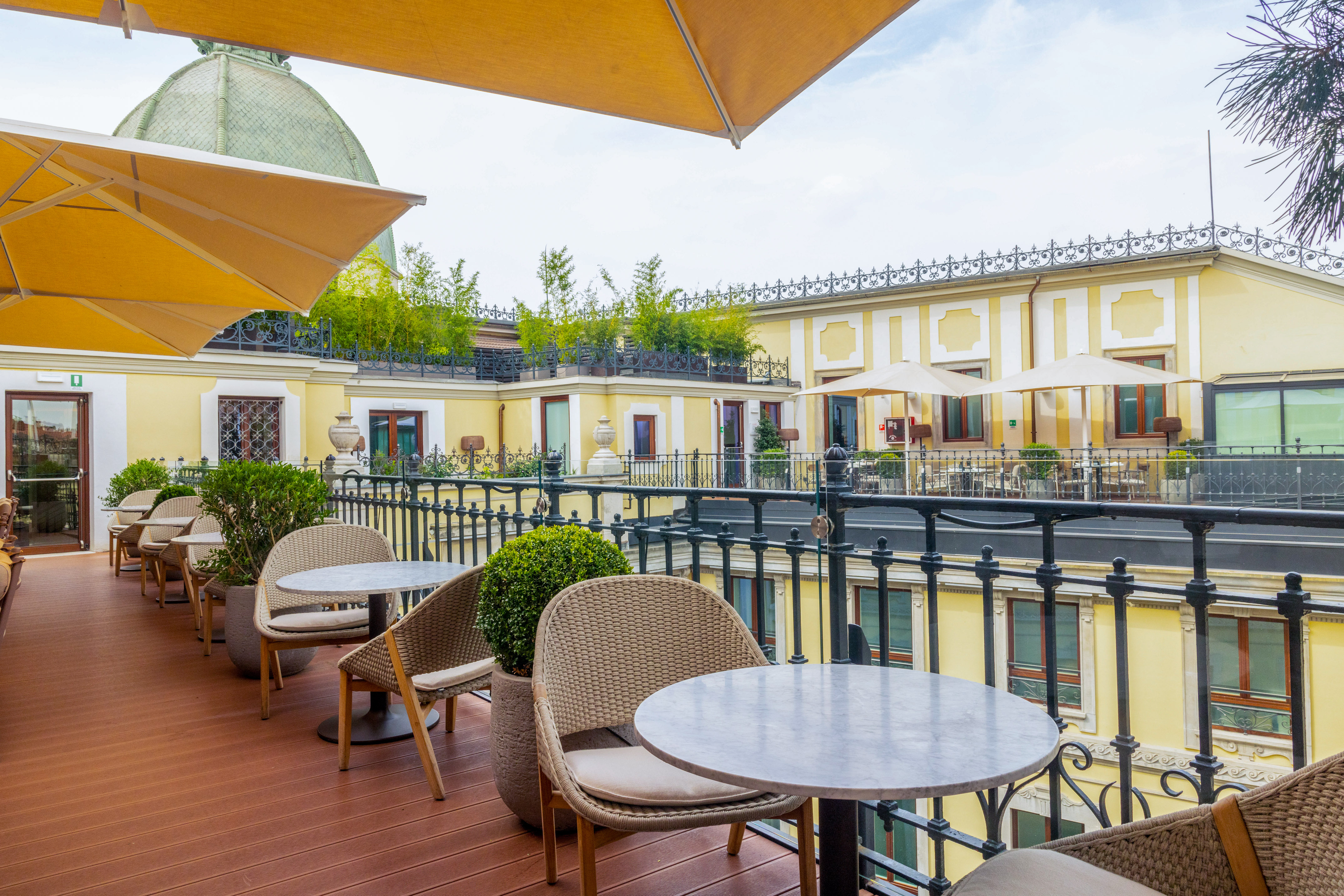 Elegant rooftop terrace: outdoor seating, yellow umbrellas, classic architecture.