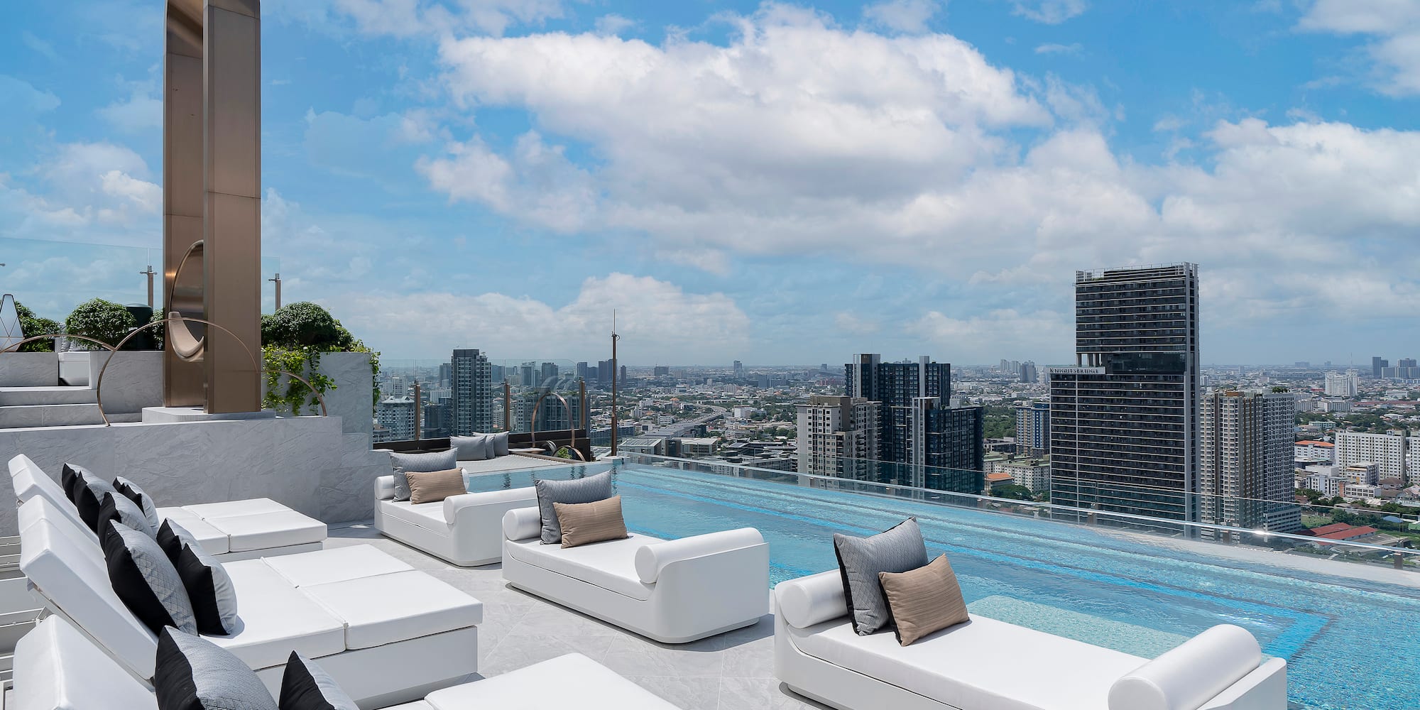 a rooftop pool with white couches and a city view