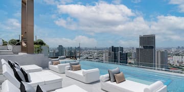 a rooftop pool with white couches and a city view
