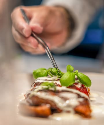 a person holding a fork over food