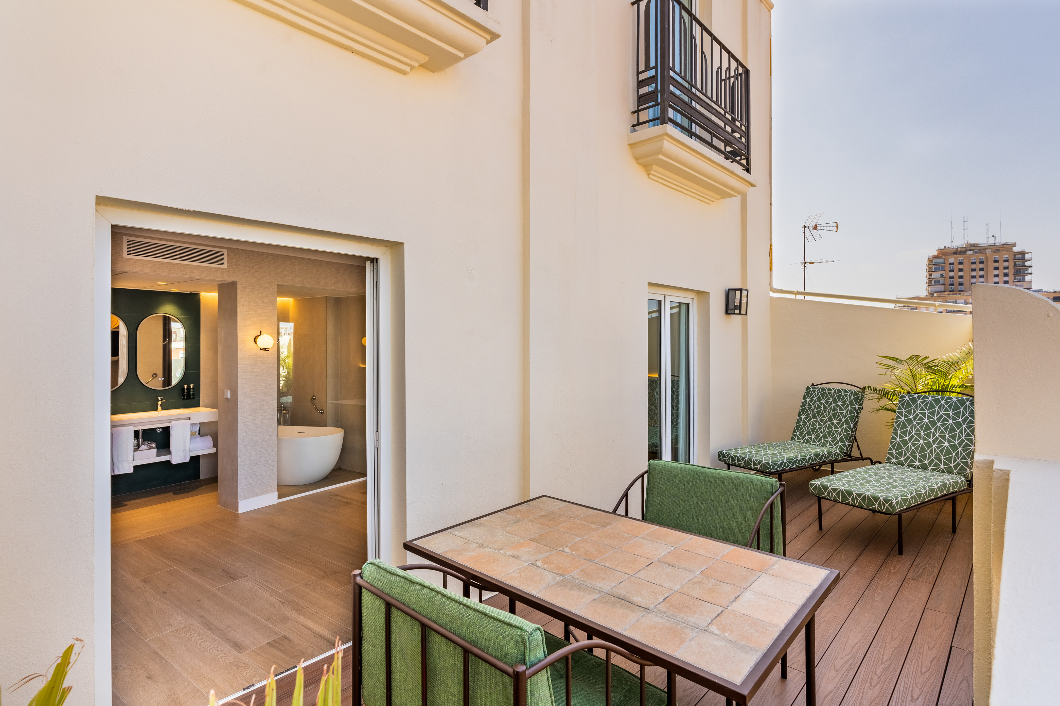 Hotel suite patio with outdoor seating and modern open-plan bathroom.