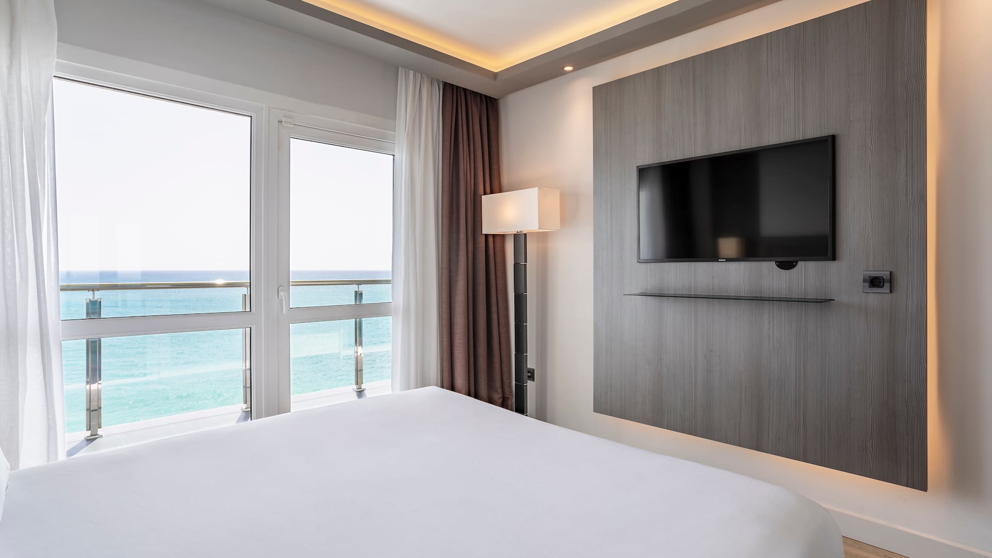 a room with a television and a view of the ocean