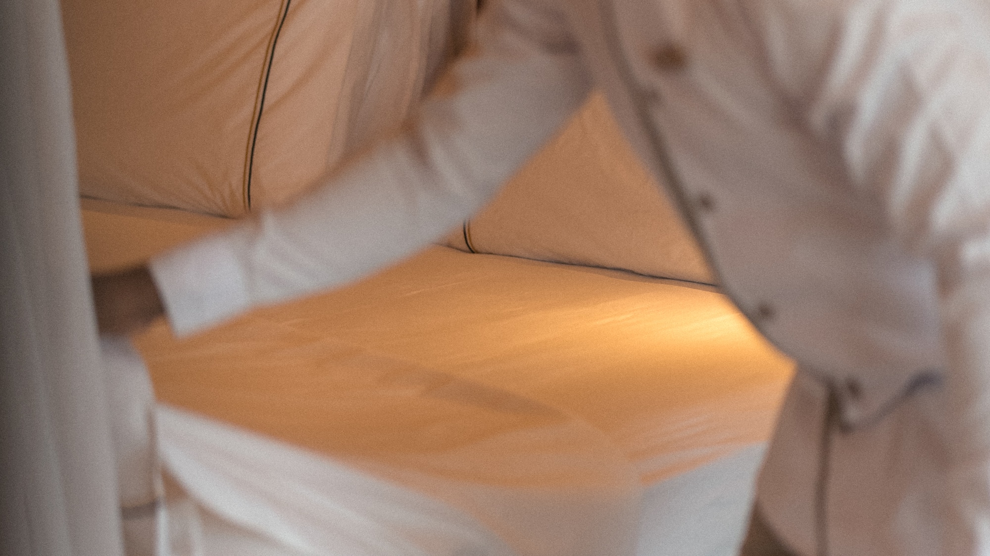 Housekeeping staff neatly making a bed with fresh white sheets.