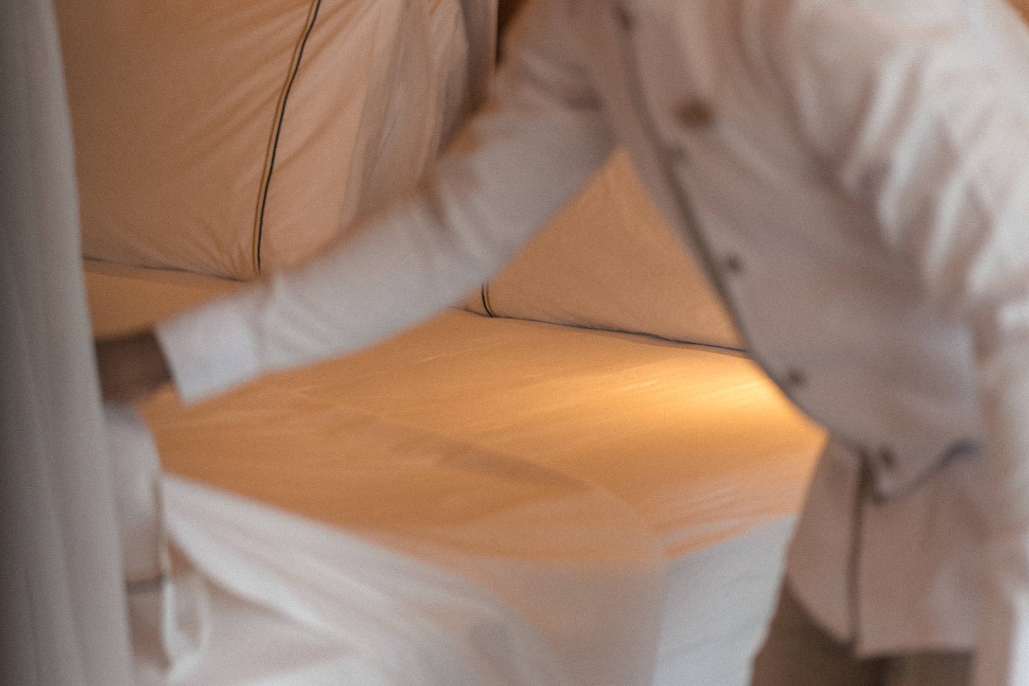 Housekeeping staff neatly making a bed with fresh white sheets.