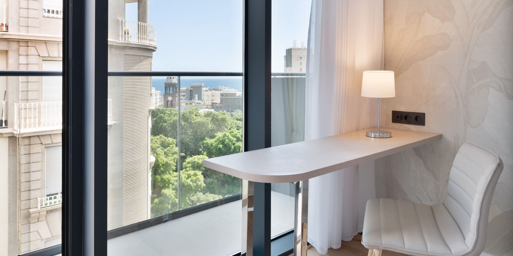 a desk with a lamp and a chair in a room with a balcony