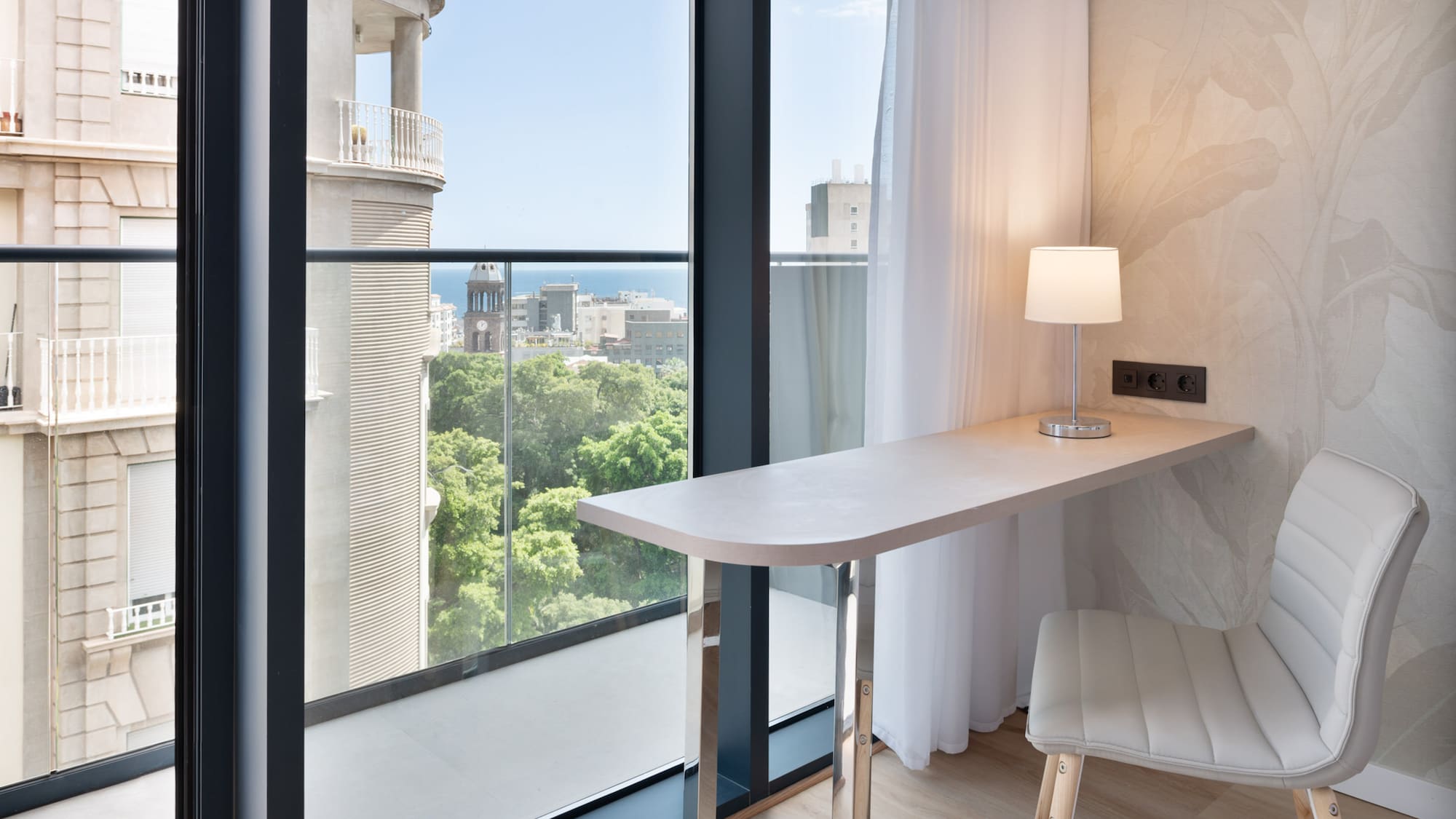 a desk with a lamp and a chair in a room with a balcony