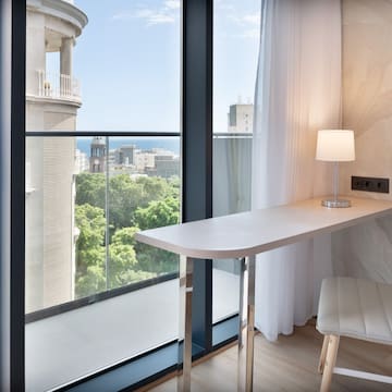 a desk with a lamp and a chair in a room with a balcony