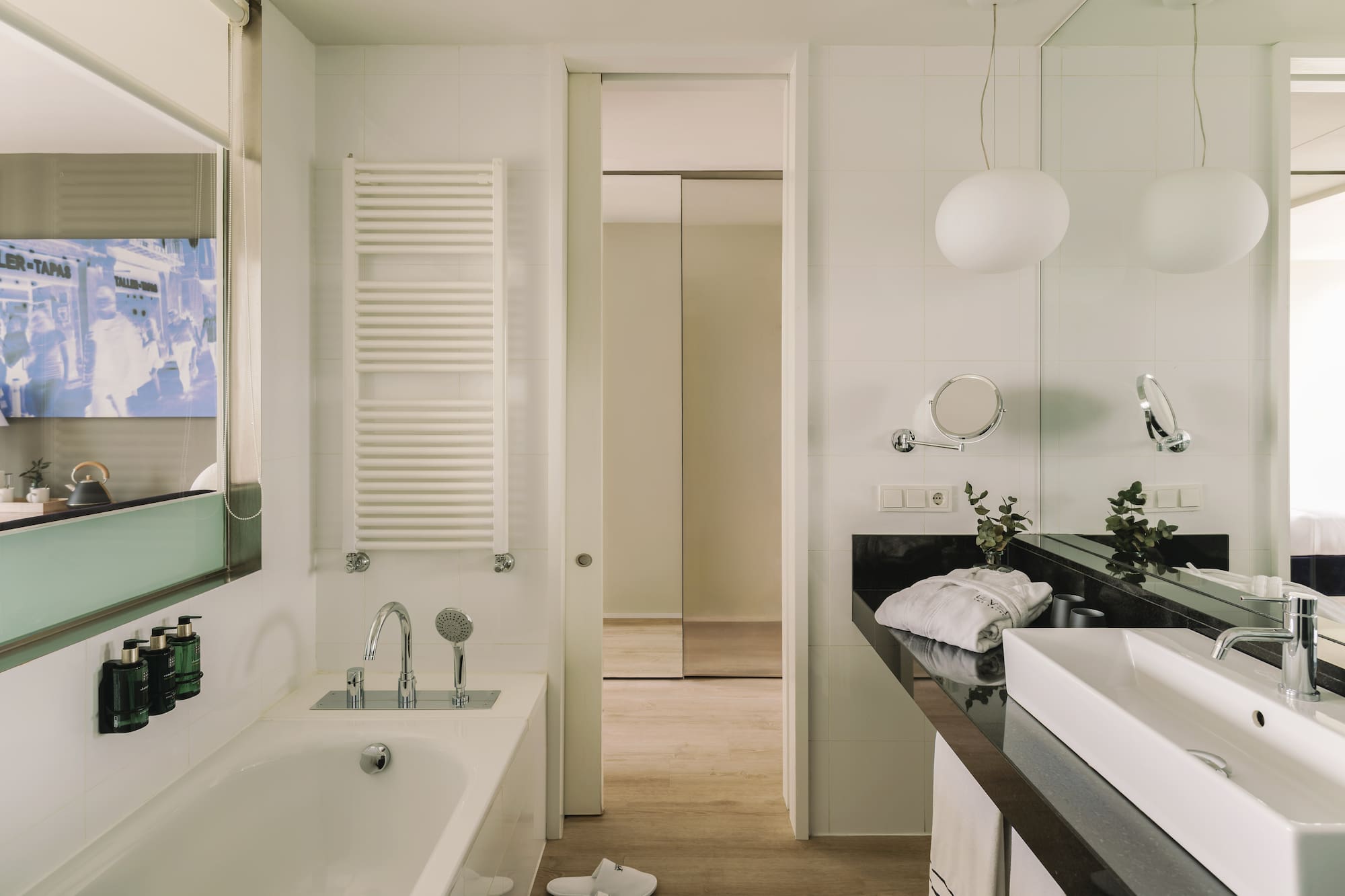 Baño moderno de hotel con bañera, lavabo y toallero.
