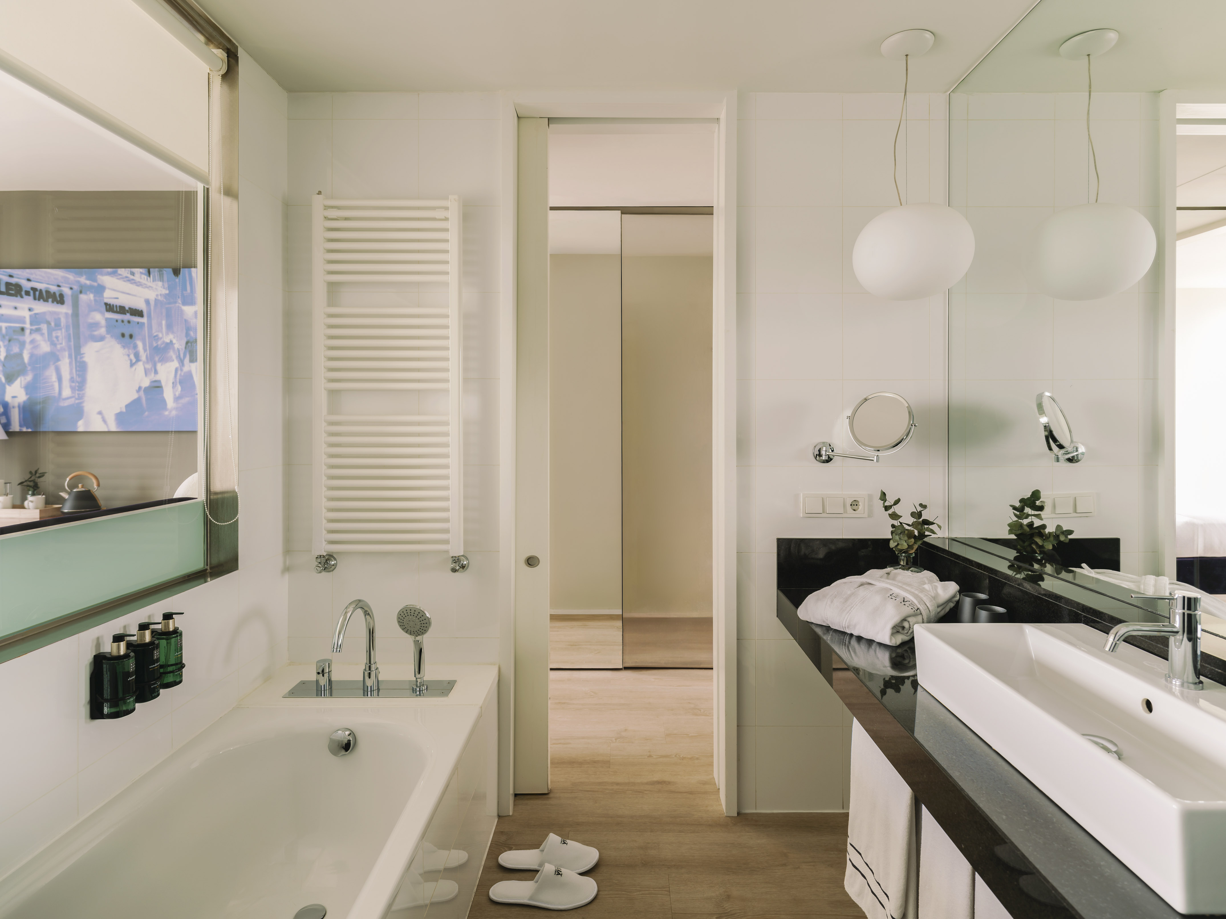Baño moderno de hotel con bañera, lavabo y toallero.