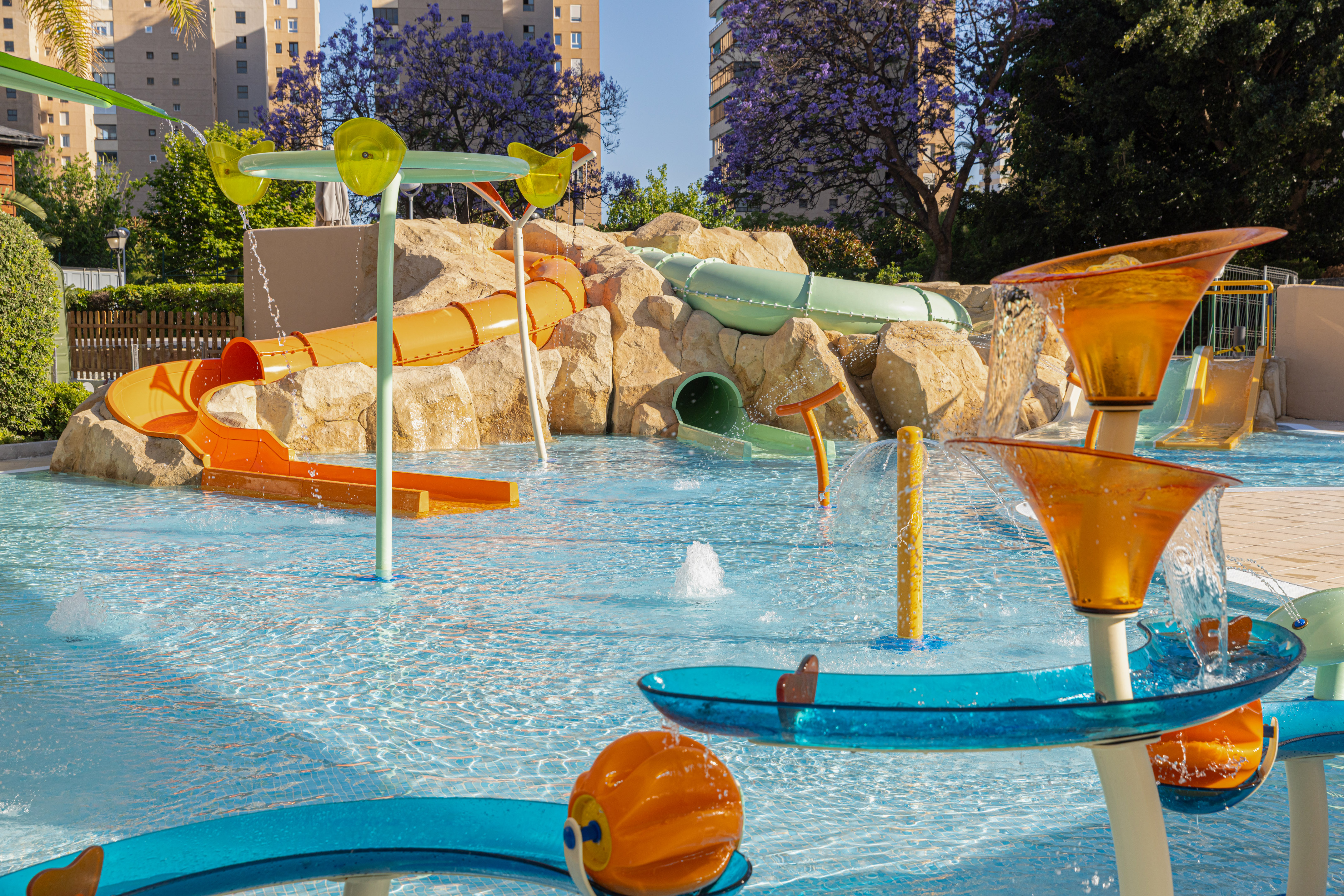 Colorful resort water park with slides, splash features, and shallow pool.