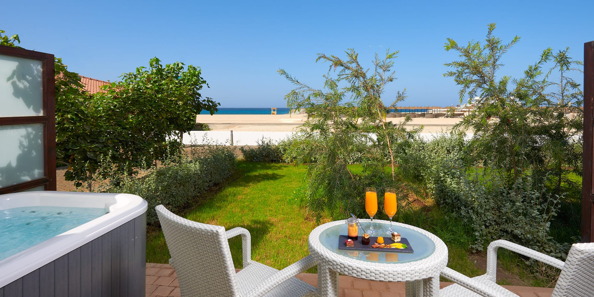 a table and chairs on a patio with a hot tub and a beach