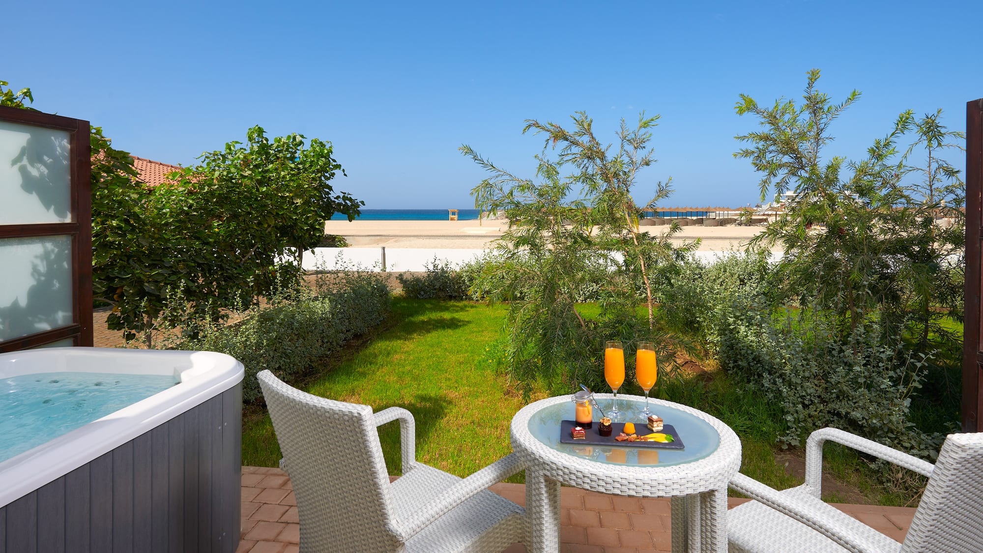 a table and chairs on a patio with a hot tub and a beach