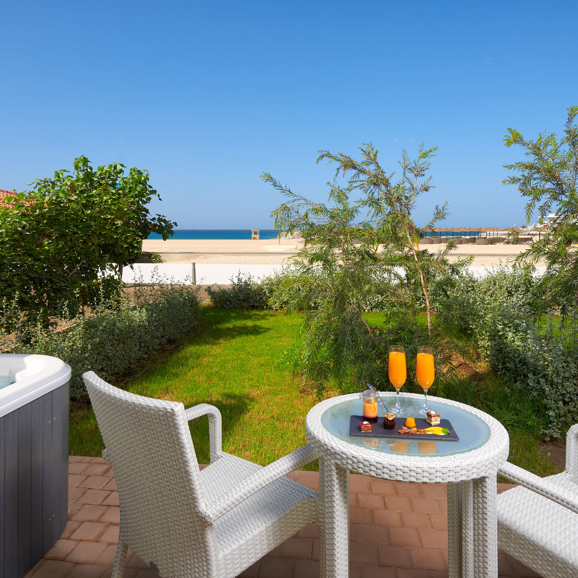 a table and chairs on a patio with a hot tub and a beach