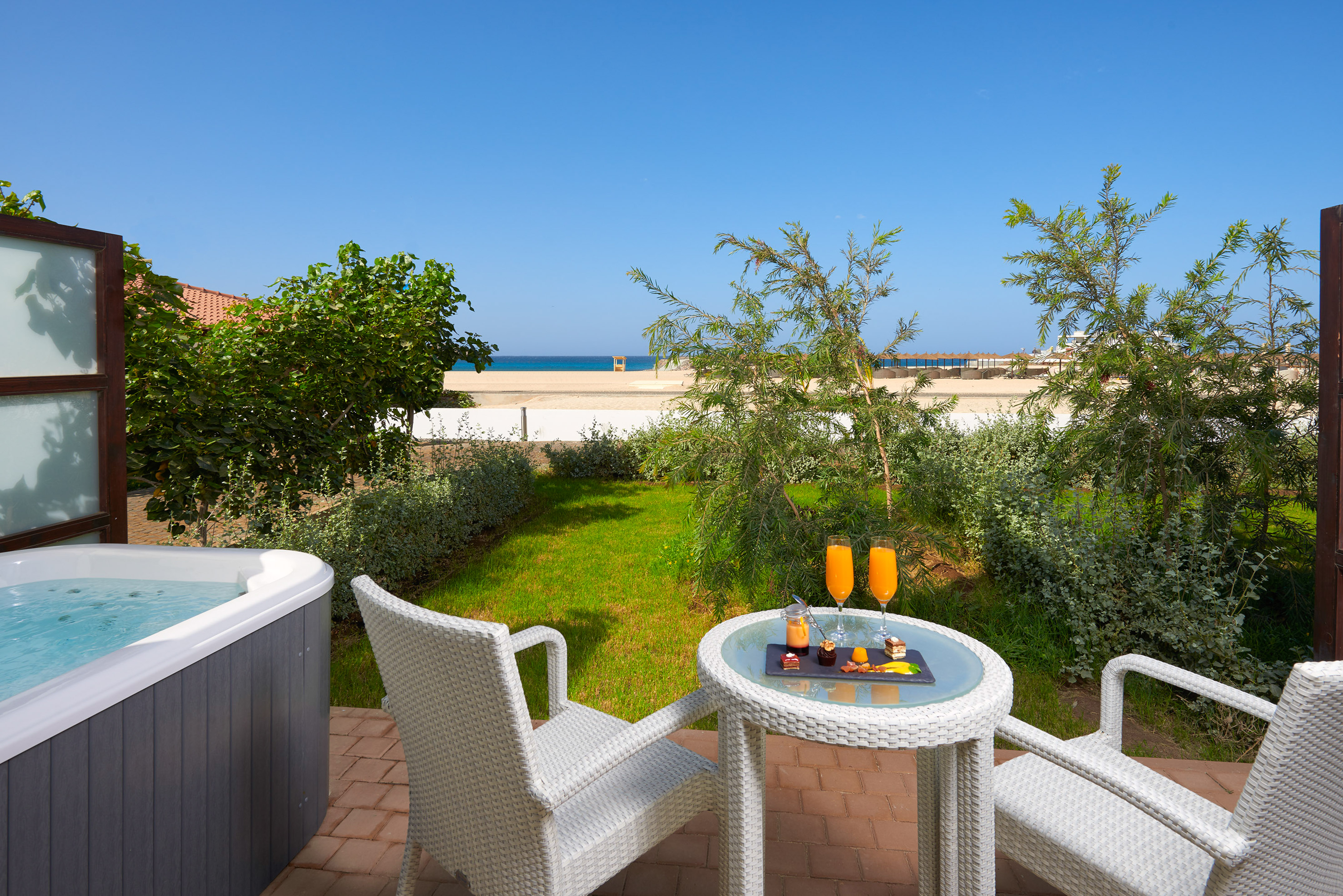 a table and chairs on a patio with a hot tub and a beach