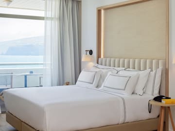 a bed with white sheets and pillows