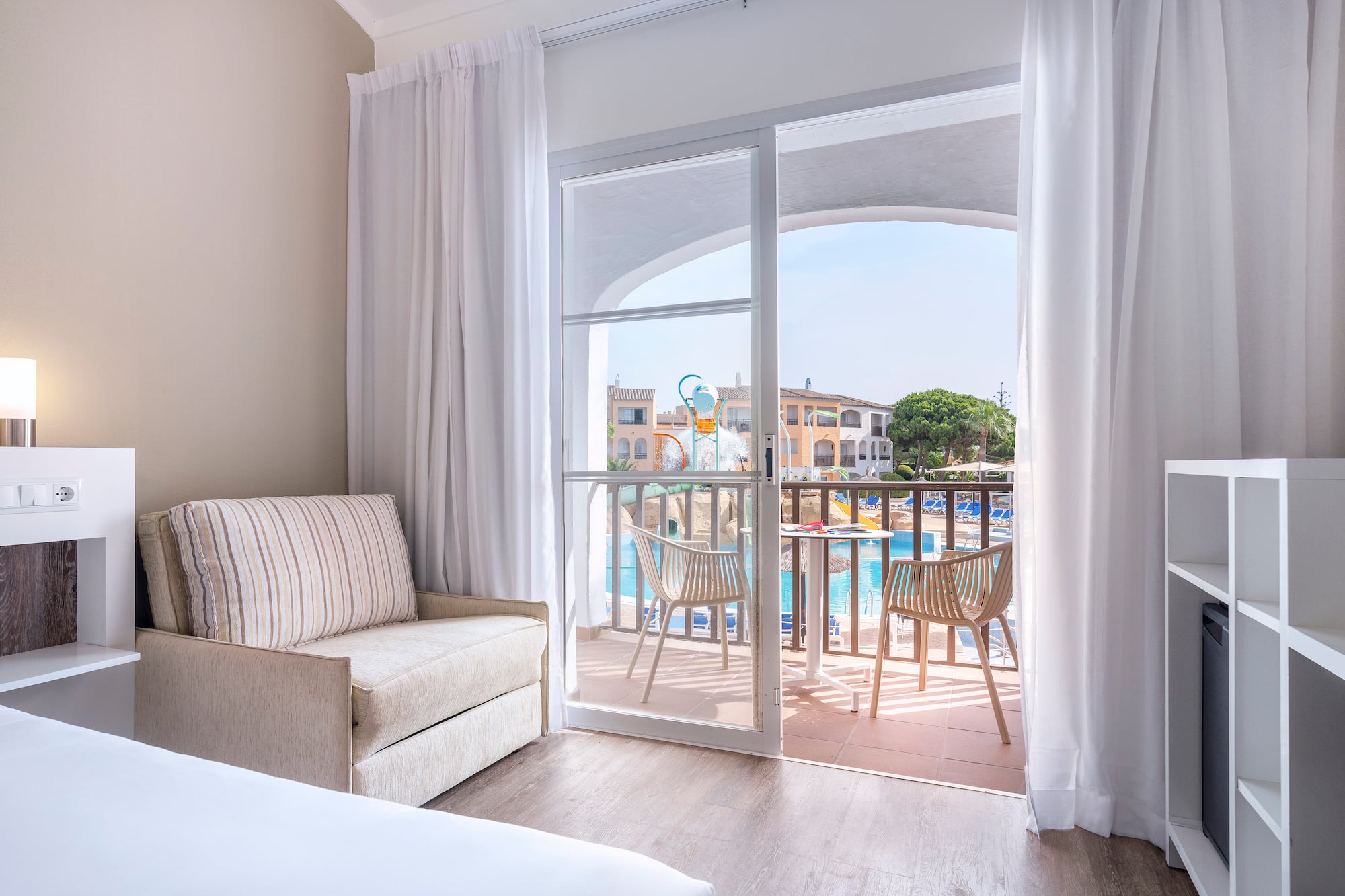 a room with a bed and a chair and a pool