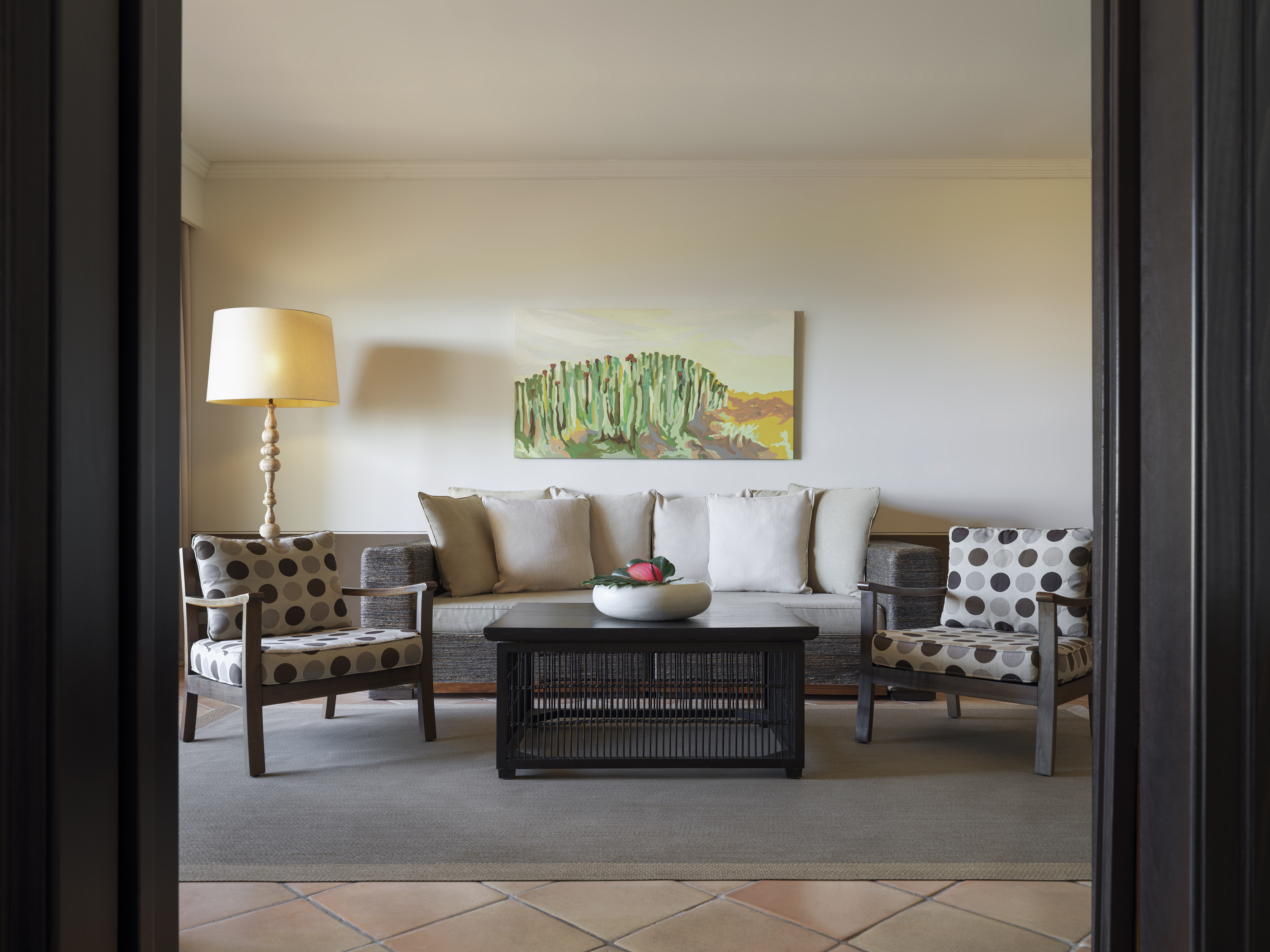 Living room with sofa, polka dot armchairs, coffee table, and cactus art.
