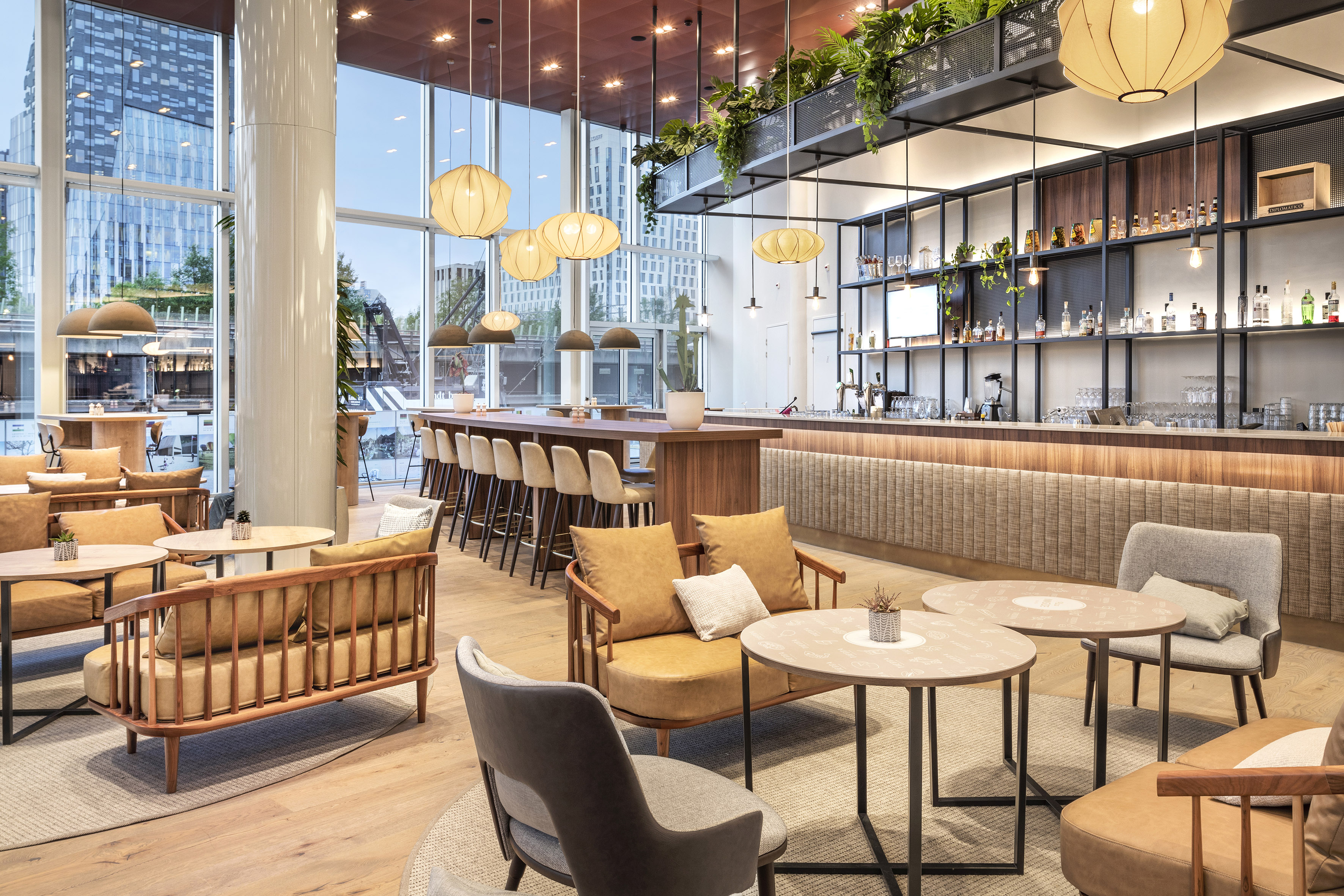 Modern lounge bar with seating, large windows, and city views.