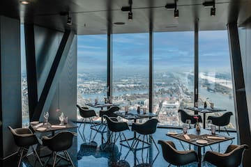 a room with tables and chairs and a view of a city and water