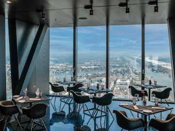 a room with tables and chairs and a view of a city and water