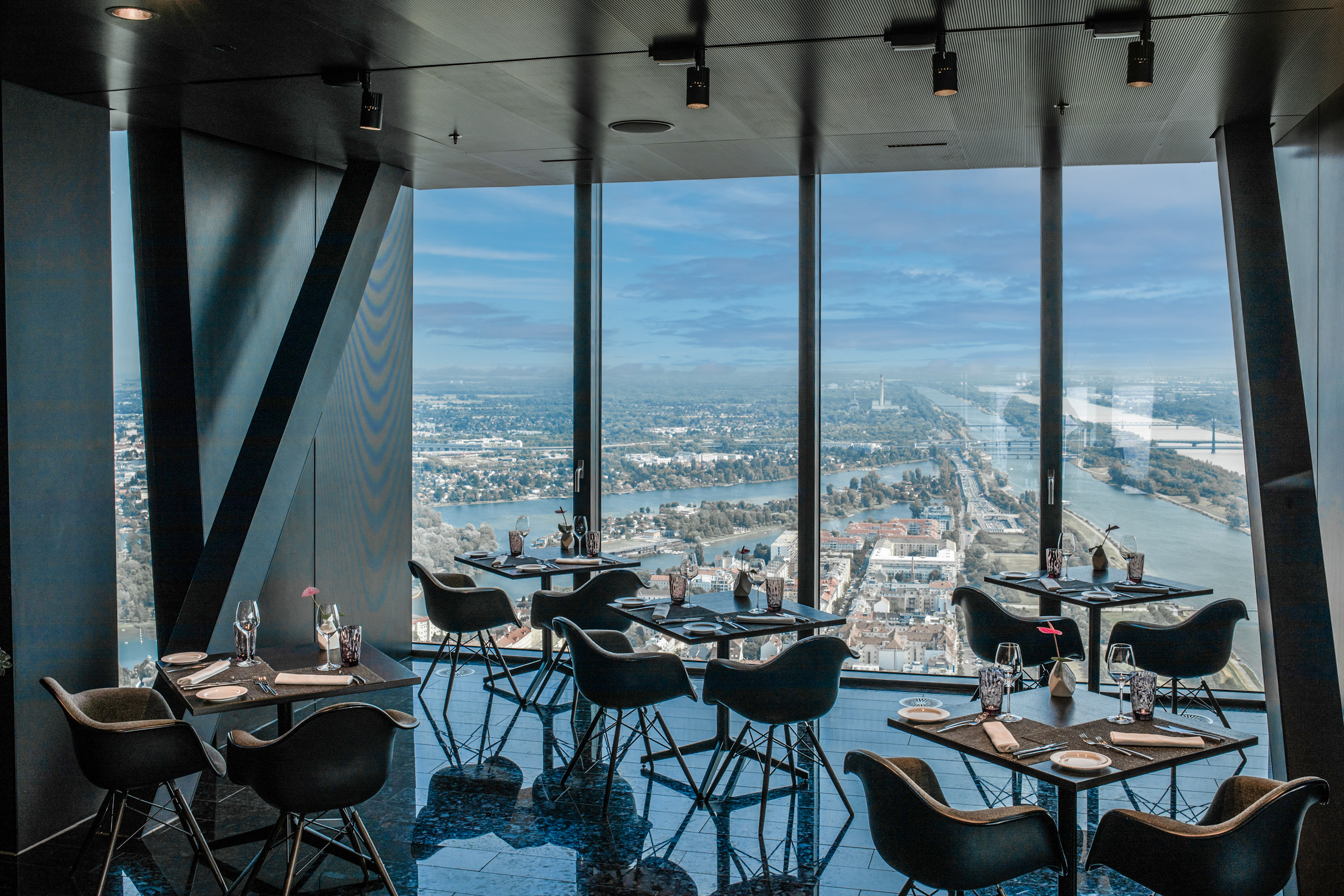 High-rise restaurant with panoramic city and river views, modern design.