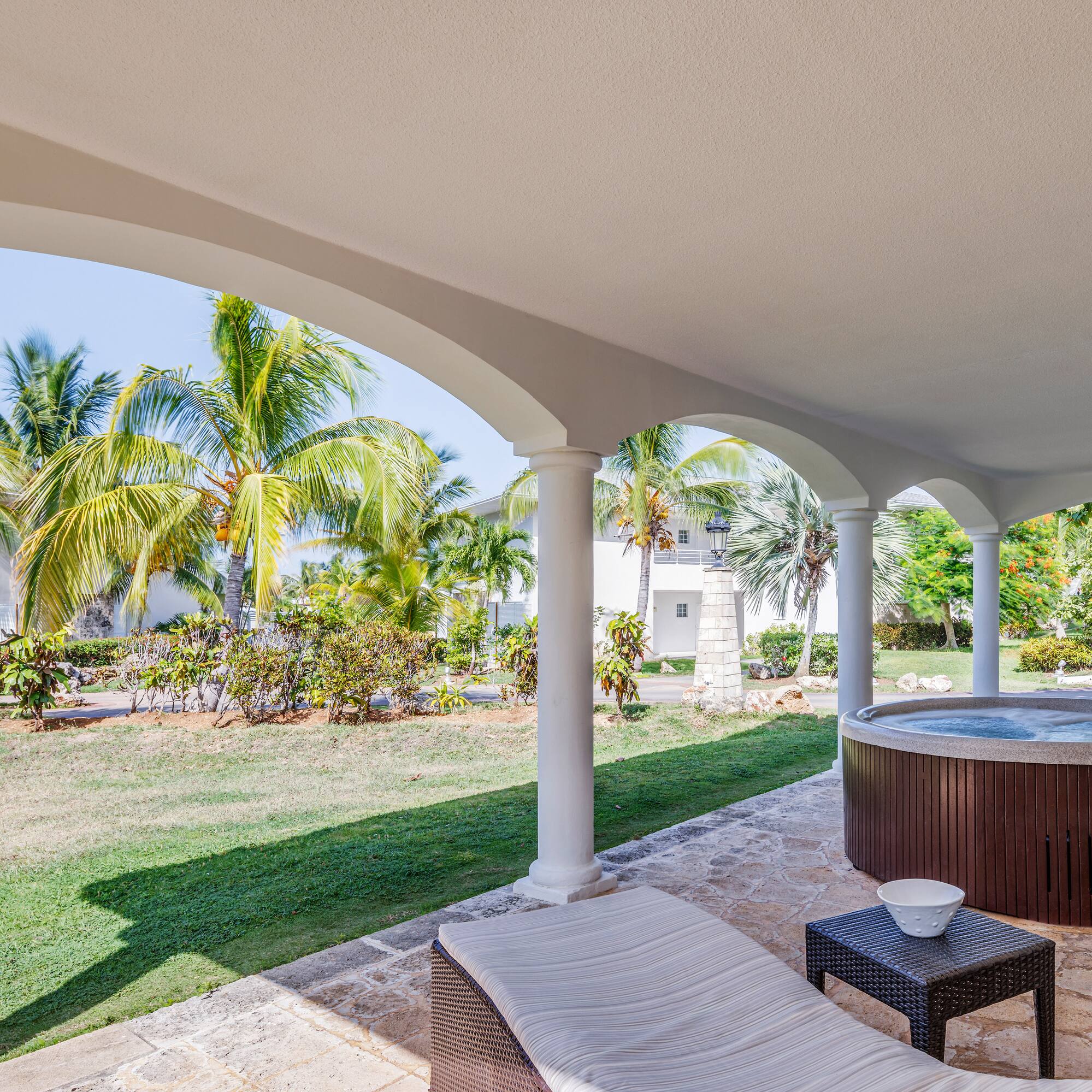 a hot tub with a table and chairs on a patio with palm trees